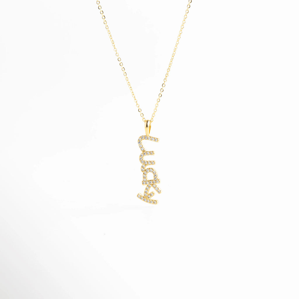 Collar dorado con dije lucky con zirconias sobre fondo blanco, Gargantilla fina dorada con colgante lucky brillante, Collar minimalista con dije lucky incrustado con zirconias, Collar de cobre chapado en oro con dije lucky elegante, Collar delicado con palabra lucky y zirconias brillantes