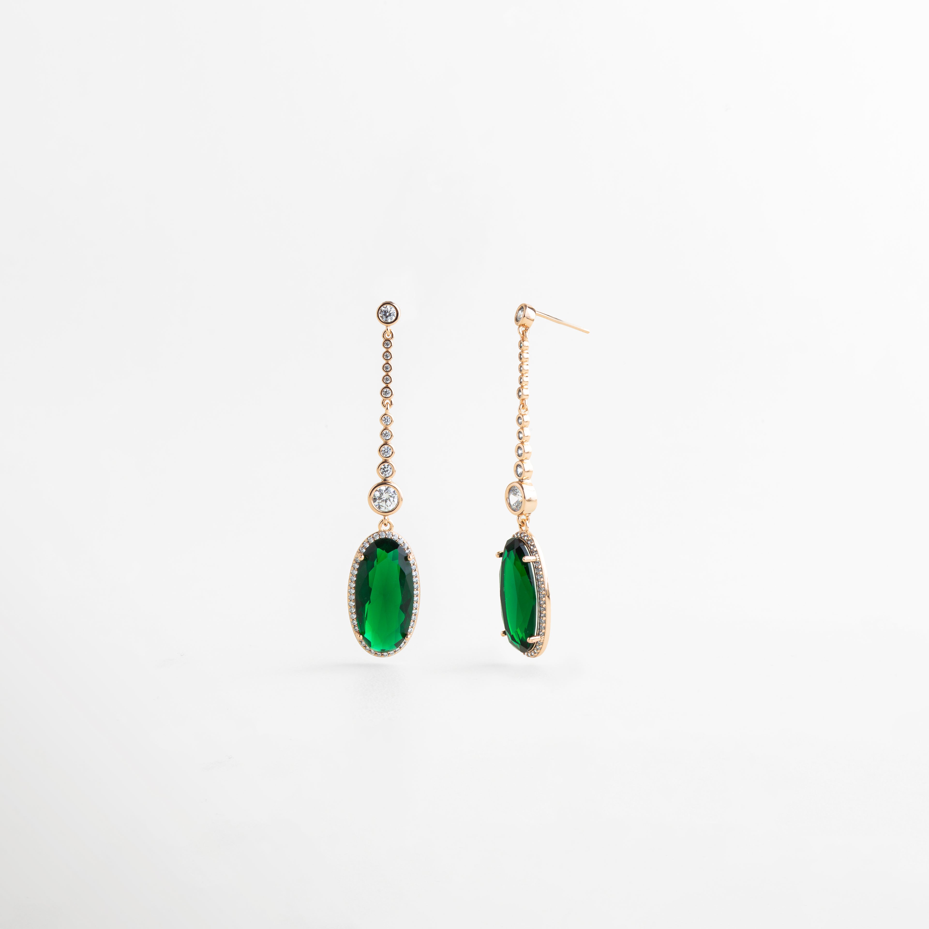 Vista completa de aretes dorados de 6 cm con piedra verde colgante y detalles brillantes, Aretes largos con base de cobre, recubrimiento dorado y piedra preciosa artificial verde, Pendientes femeninos con silueta alargada y colgante verde ovalado en acabado elegante, Aretes delicados con brillo sutil y piedra verde intensa, presentados en vista frontal, Diseño de aretes colgantes en tono oro con piedra verde y acabado sofisticado.
