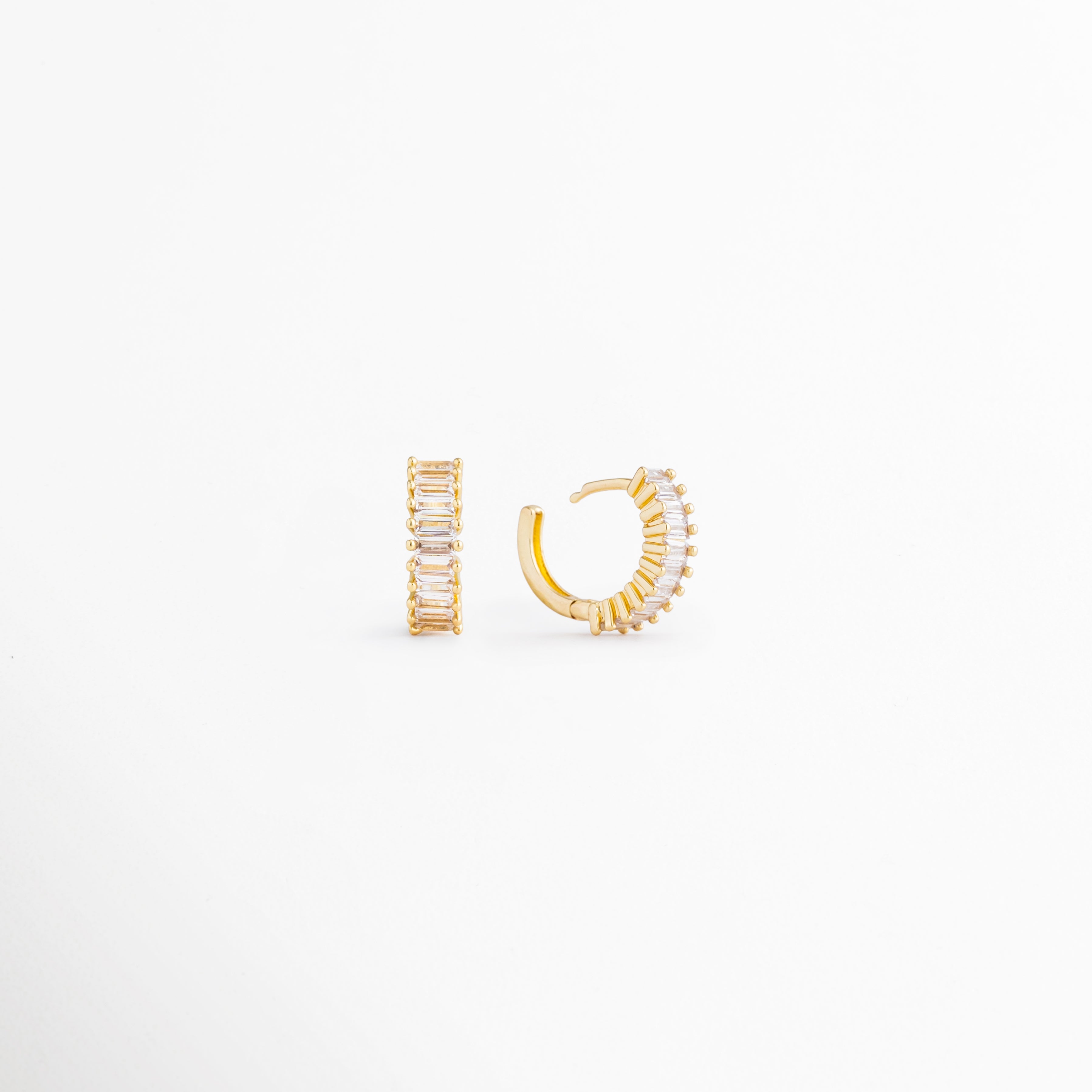 Isabel Golden Hoops desde ángulo lateral mostrando sus zirconias brillantes, Detalle de arracadas doradas pequeñas con acabado en Oro 18K, Vista angular de hoops elegantes y versátiles para mujer, Aretes dorados con zirconias y diseño clásico contemporáneo, Detalle de arracadas compactas ideales para looks diarios.