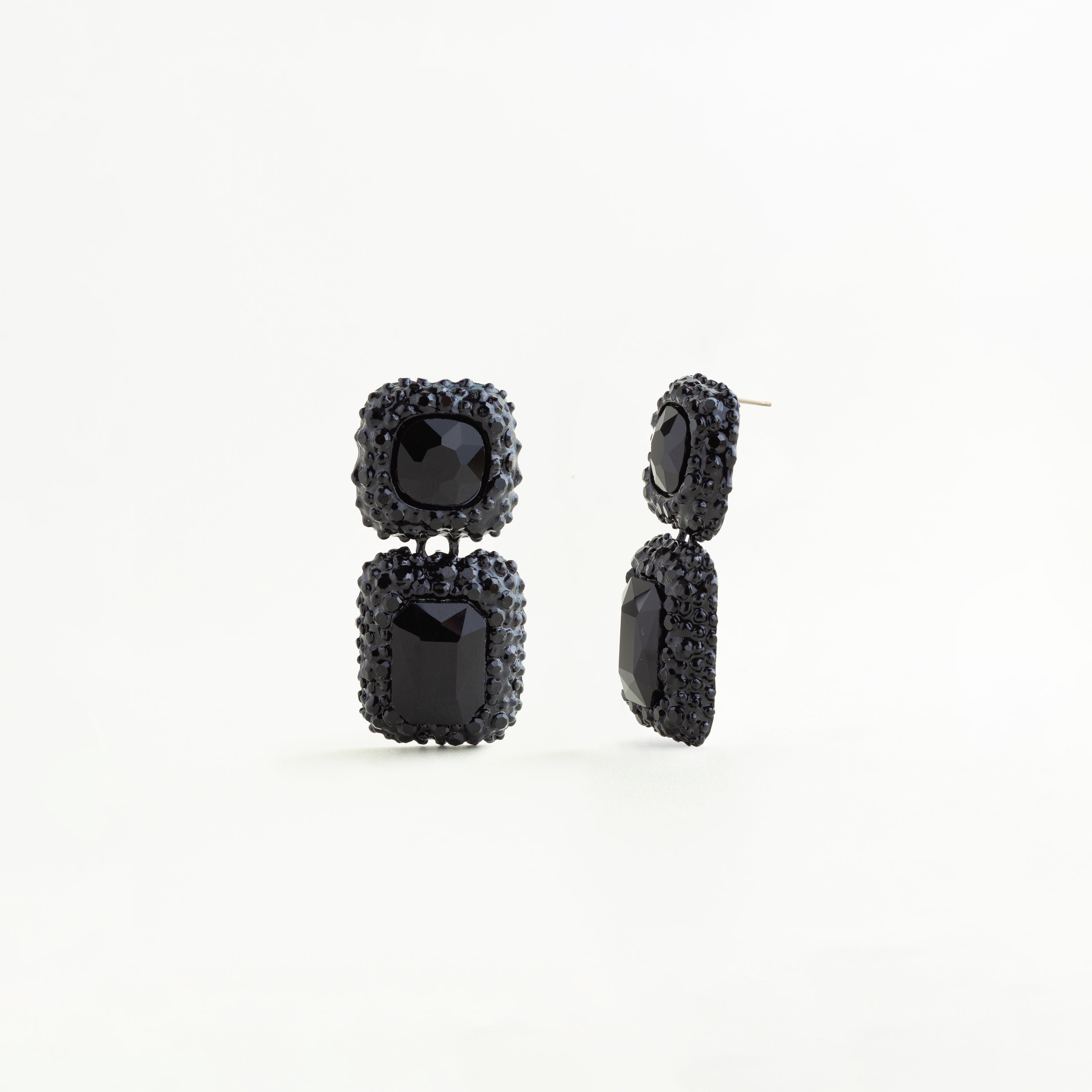 Vista lateral de aretes negros geométricos con cristales A5 y acabado brillante, Perfil de pendientes largos negros con diseño rectangular y detalles de cristales, Aretes colgantes negros vistos de lado con estructura elegante y moderna, Detalle lateral de aretes de cobre enchapado con cristales negros brillantes, Pendientes geométricos negros con diseño sofisticado y acabado de lujo vistos de perfil.