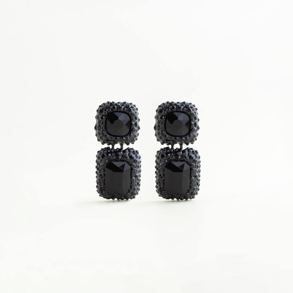 Aretes largos negros con cristales A5 y diseño geométrico doble en acabado brillante, pendientes negros de cobre enchapado con cristales cuadrados y rectangulares estilo elegante, Aretes statement color negro con incrustaciones brillantes y forma geométrica sofisticada, Joyería femenina con aretes negros de cristales A5 y diseño colgante moderno, Aretes glam negros con estructura geométrica y acabado brillante sobre fondo blanco.