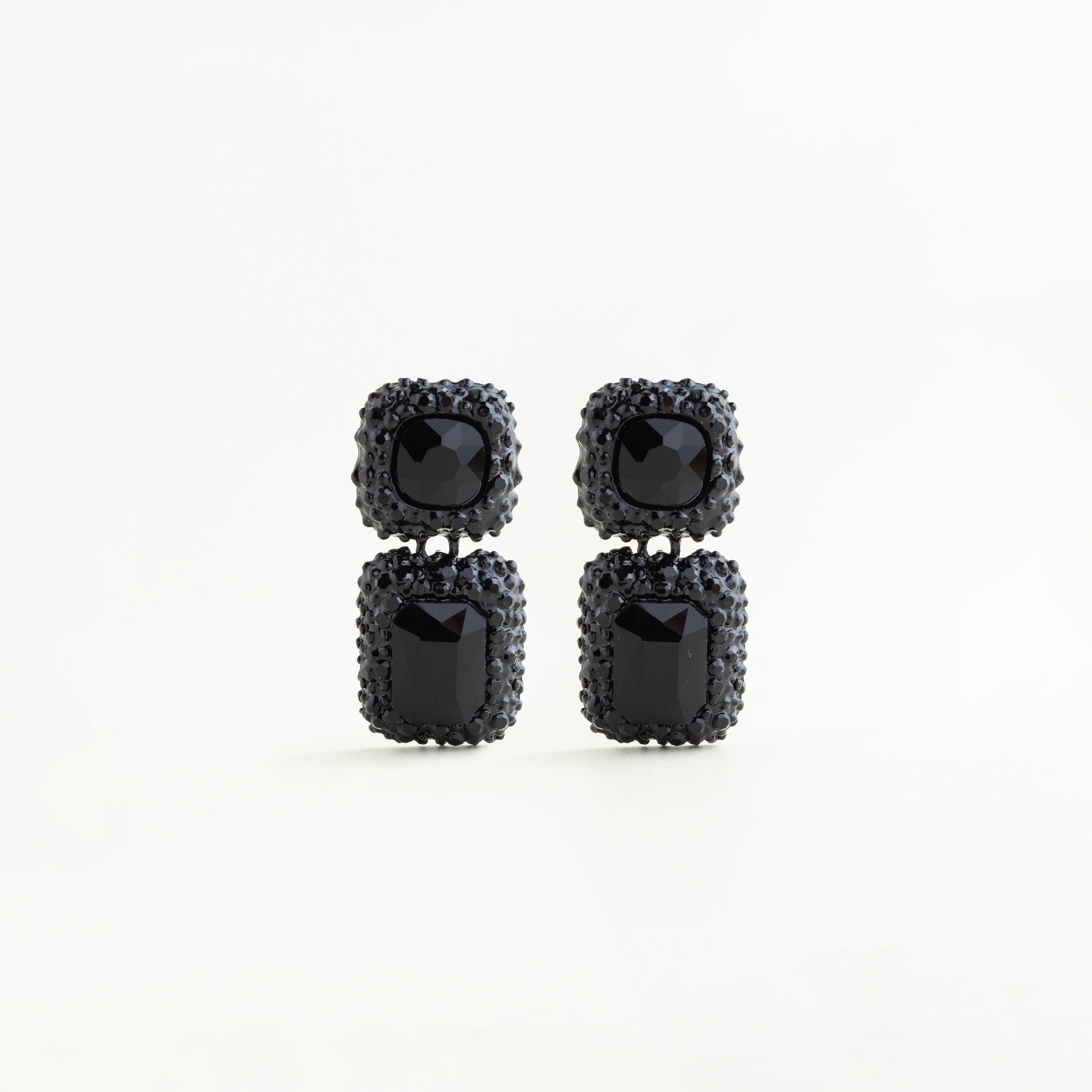 Aretes largos negros con cristales A5 y diseño geométrico doble en acabado brillante, pendientes negros de cobre enchapado con cristales cuadrados y rectangulares estilo elegante, Aretes statement color negro con incrustaciones brillantes y forma geométrica sofisticada, Joyería femenina con aretes negros de cristales A5 y diseño colgante moderno, Aretes glam negros con estructura geométrica y acabado brillante sobre fondo blanco.