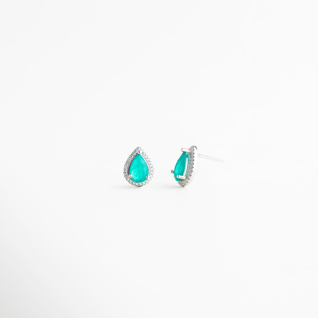 Vista lateral de aretes tipo lágrima en plata con piedra turquesa brillante, Perfil de pendientes pequeños con diseño elegante y acabado en plata enchapada, Aretes de plata 925 con cristales sintéticos vistos de lado sobre fondo blanco, Detalle lateral de pendientes tipo gota con brillo sofisticado y diseño minimalista, Aretes delicados con piedra turquesa y estructura de plata vistos de perfil.