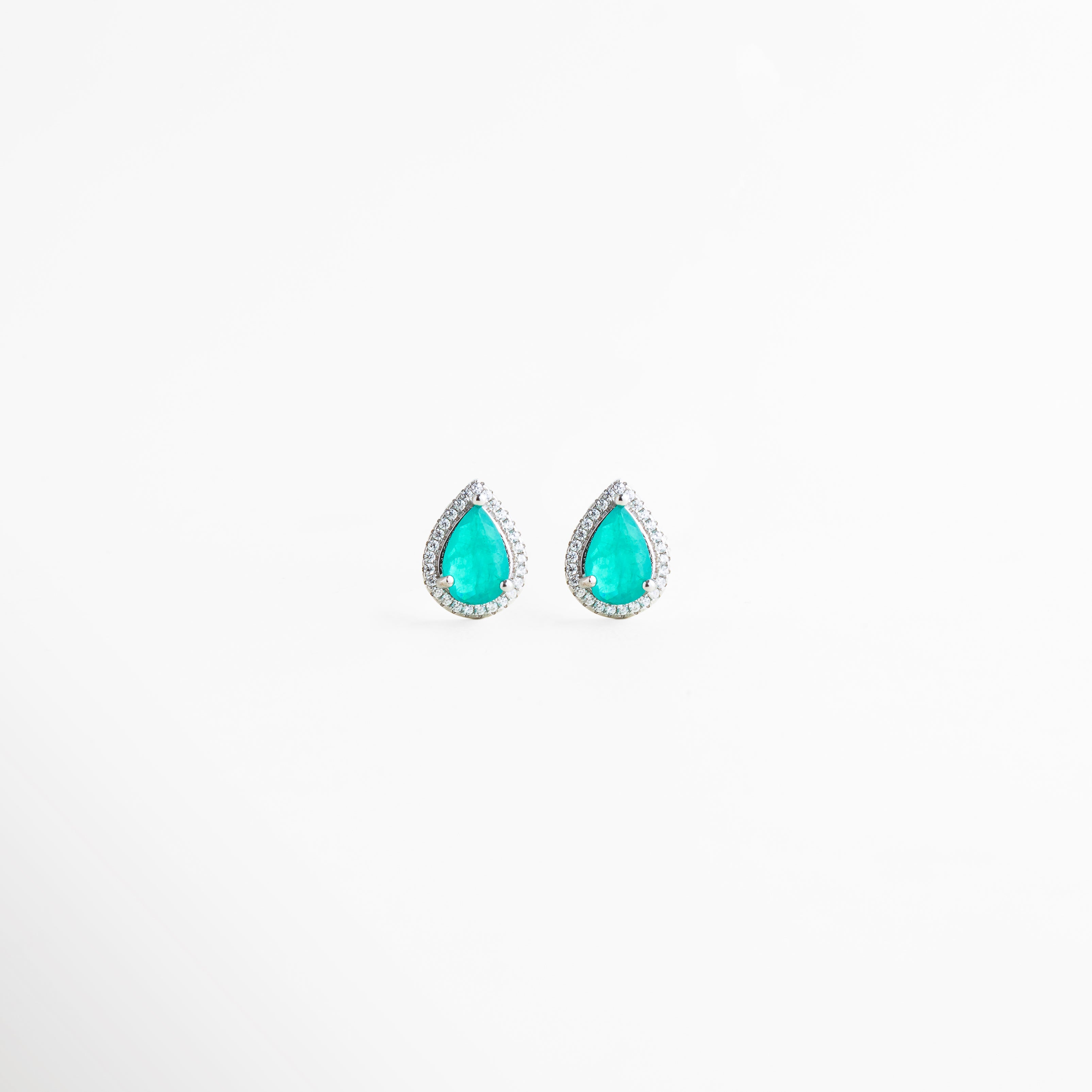 Aretes tipo gota en plata 925 con piedra turquesa y halo de diamantes sintéticos, Pendientes pequeños de plata con diseño de lágrima y cristales brillantes alrededor, Aretes elegantes color turquesa con incrustaciones de diamantes sintéticos en plata, Joyería fina con aretes de gota turquesa y acabado brillante en plata enchapada, Aretes delicados de plata ley 925 con piedra azul verdosa y detalles brillantes.