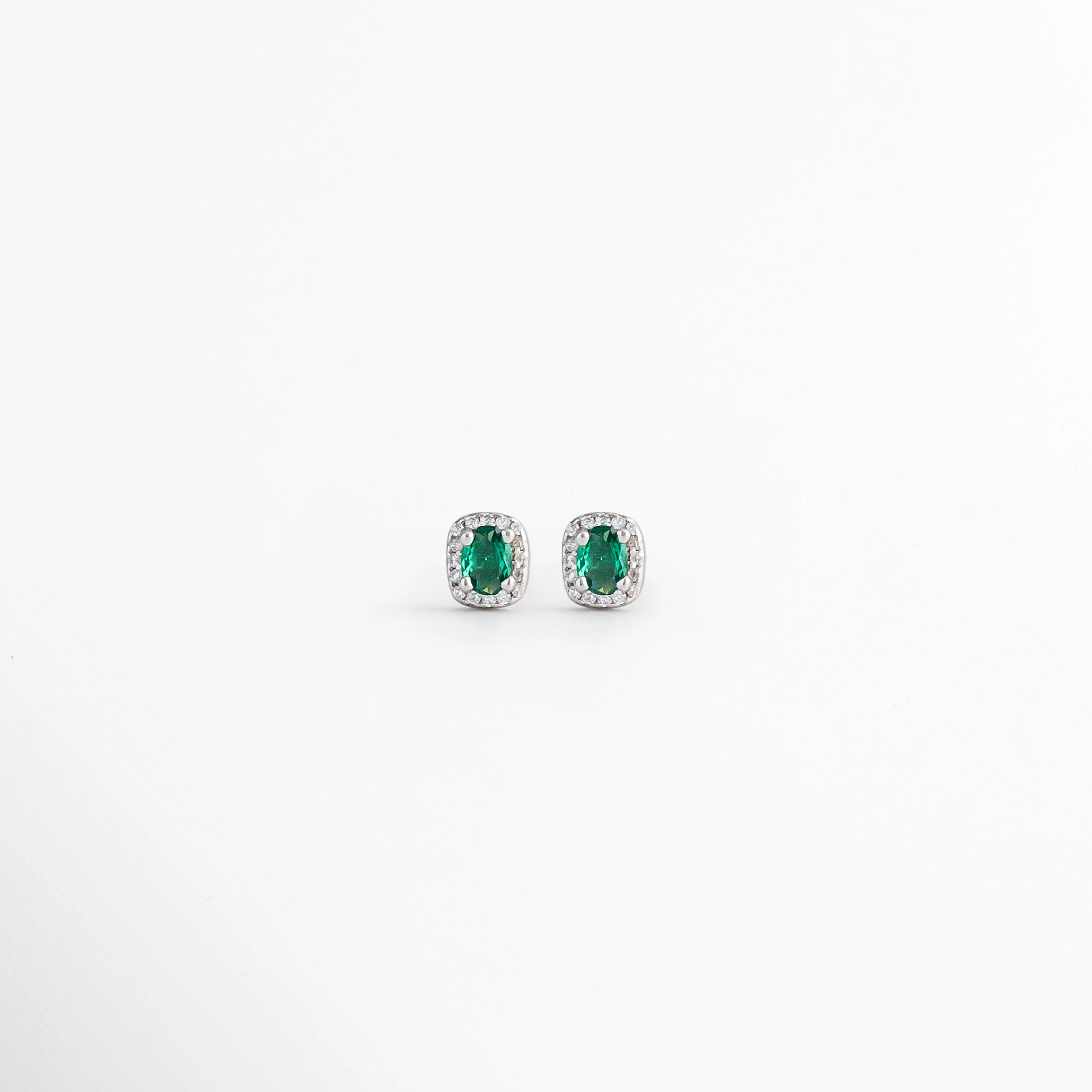 Aretes Alana Studs de Plata Ley 925 con esmeralda sintética ovalada y zirconias en acabado de Plata Esterlina, Vista frontal de los Aretes Alana Studs con esmeralda sintética verde rodeada de zirconias, Aretes Alana Studs de plata con esmeralda sintética y zirconias en diseño clásico y elegante, Par de Aretes Alana Studs con piedra verde ovalada y acabado en Plata Esterlina sobre fondo blanco, Aretes Alana Studs elaborados en Plata Ley 925 con esmeralda sintética y zirconias brillantes.