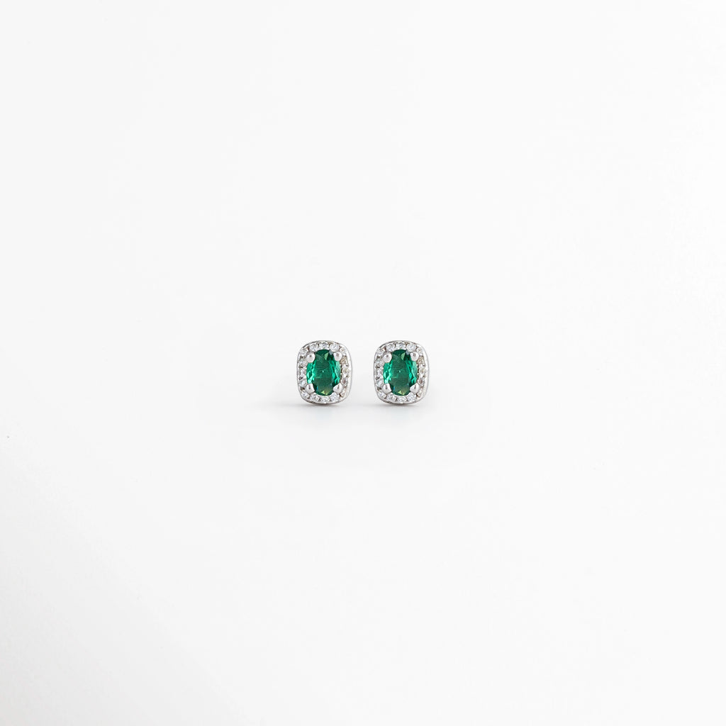 Aretes Alana Studs de Plata Ley 925 con esmeralda sintética ovalada y zirconias en acabado de Plata Esterlina, Vista frontal de los Aretes Alana Studs con esmeralda sintética verde rodeada de zirconias, Aretes Alana Studs de plata con esmeralda sintética y zirconias en diseño clásico y elegante, Par de Aretes Alana Studs con piedra verde ovalada y acabado en Plata Esterlina sobre fondo blanco, Aretes Alana Studs elaborados en Plata Ley 925 con esmeralda sintética y zirconias brillantes.