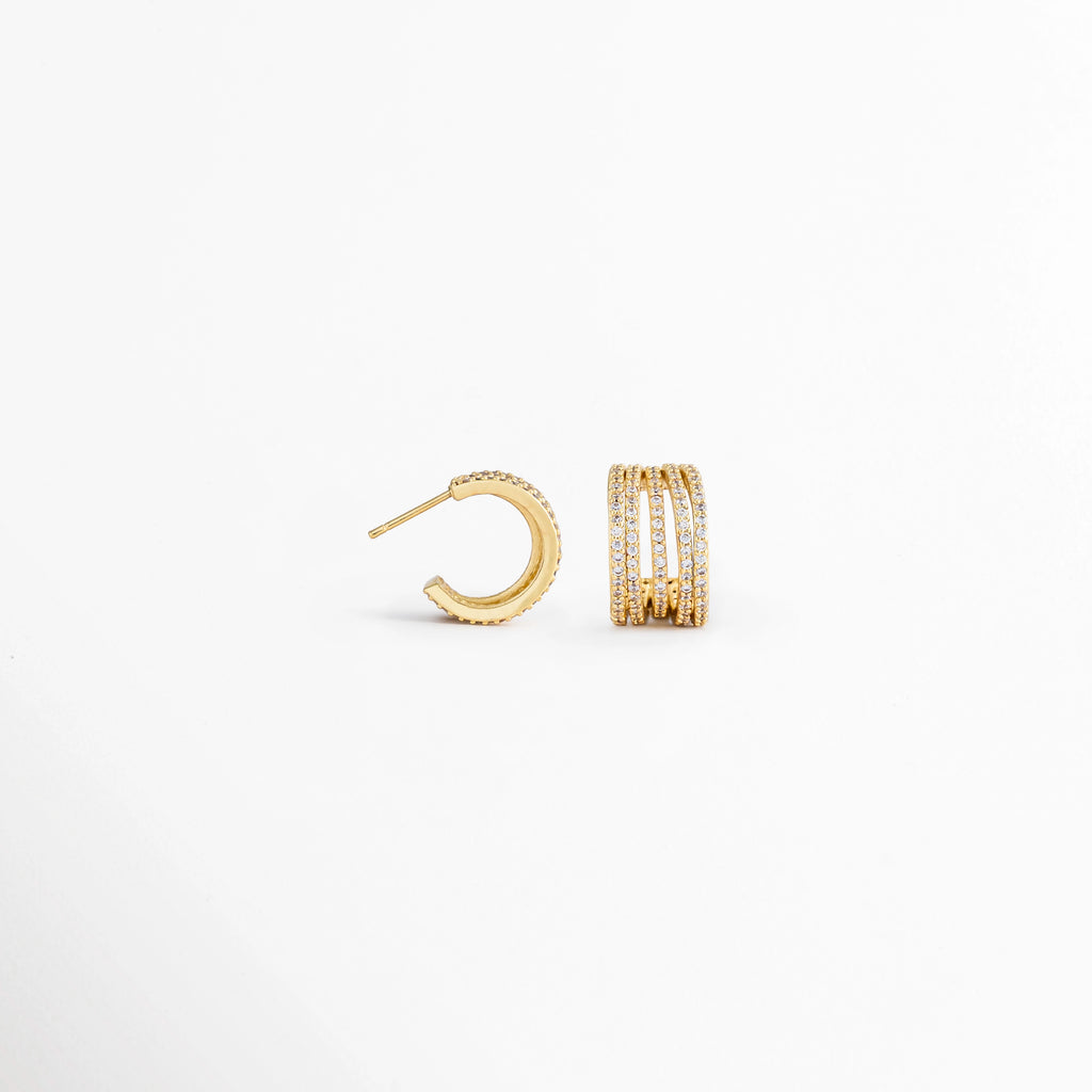 Vista lateral de los Aretes Jovovich Golden Hoops mostrando el broche y el grosor del aro, Perfil de los Aretes Jovovich Golden Hoops con acabado dorado brillante y cierre tipo bisagra, Aretes Jovovich Golden Hoops en vista lateral destacando la estructura del aro y su textura, Detalle lateral de los Aretes Jovovich Golden Hoops elaborados en cobre con recubrimiento en Oro, Vista de costado de los Aretes Jovovich Golden Hoops con diseño tipo huggie y acabado dorado.