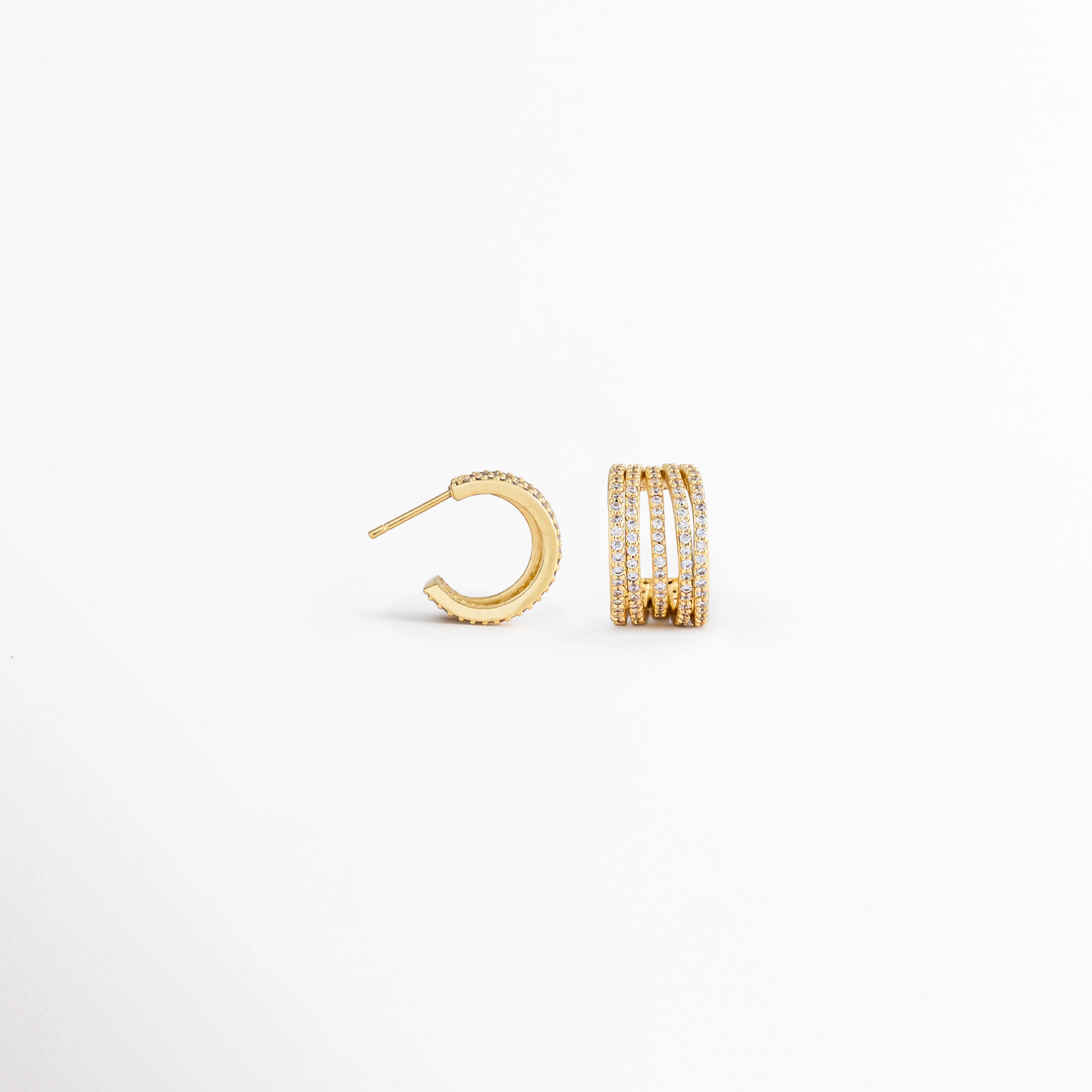 Vista lateral de los Aretes Jovovich Golden Hoops mostrando el broche y el grosor del aro, Perfil de los Aretes Jovovich Golden Hoops con acabado dorado brillante y cierre tipo bisagra, Aretes Jovovich Golden Hoops en vista lateral destacando la estructura del aro y su textura, Detalle lateral de los Aretes Jovovich Golden Hoops elaborados en cobre con recubrimiento en Oro, Vista de costado de los Aretes Jovovich Golden Hoops con diseño tipo huggie y acabado dorado.