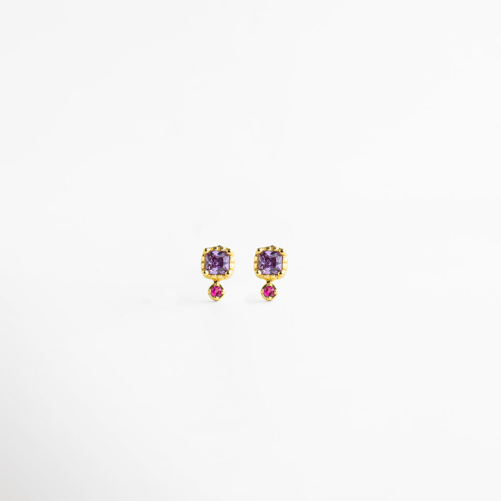 Aretes Winona Studs con zirconia violeta y zirconia fucsia en acabado dorado de 18K, Aretes pequeños dorados con zirconias en tonos violeta y fucsia, diseño delicado y femenino, Aretes tipo stud enchapados en oro 18K con zirconias de colores vibrantes, Aretes elegantes con zirconia violeta superior y zirconia fucsia inferior en diseño refinado, Aretes de latón con recubrimiento dorado y zirconias brillantes en tonos rosa y violeta.