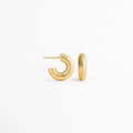 Vista lateral de los Aretes Golden Shell Hoops mostrando el cierre tipo bisagra y el perfil del aro, Perfil de los Aretes Golden Shell Hoops con acabado en Oro 18K y diseño acanalado, Aretes Golden Shell Hoops en vista lateral destacando el sistema de cierre y la textura del aro, Detalle lateral de los Aretes Golden Shell Hoops elaborados en acero inoxidable con acabado dorado, Vista de costado de los Aretes Golden Shell Hoops con diseño tipo huggie y acabado brillante.