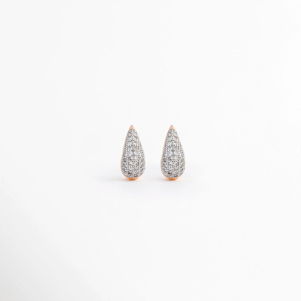 Aretes Zarya Golden Hoops de cobre con recubrimiento en Oro 18K e incrustaciones de zirconias sobre fondo blanco, Vista frontal de los Aretes Zarya Golden Hoops con diseño tipo huggie y zirconias brillantes, Aretes Zarya Golden Hoops con acabado en Oro 18K y detalle de zirconias incrustadas, Par de Aretes Zarya Golden Hoops con diseño elegante tipo aro y zirconias en acabado dorado, Aretes dorados Zarya Golden Hoops con zirconias y diseño clásico para mujer.