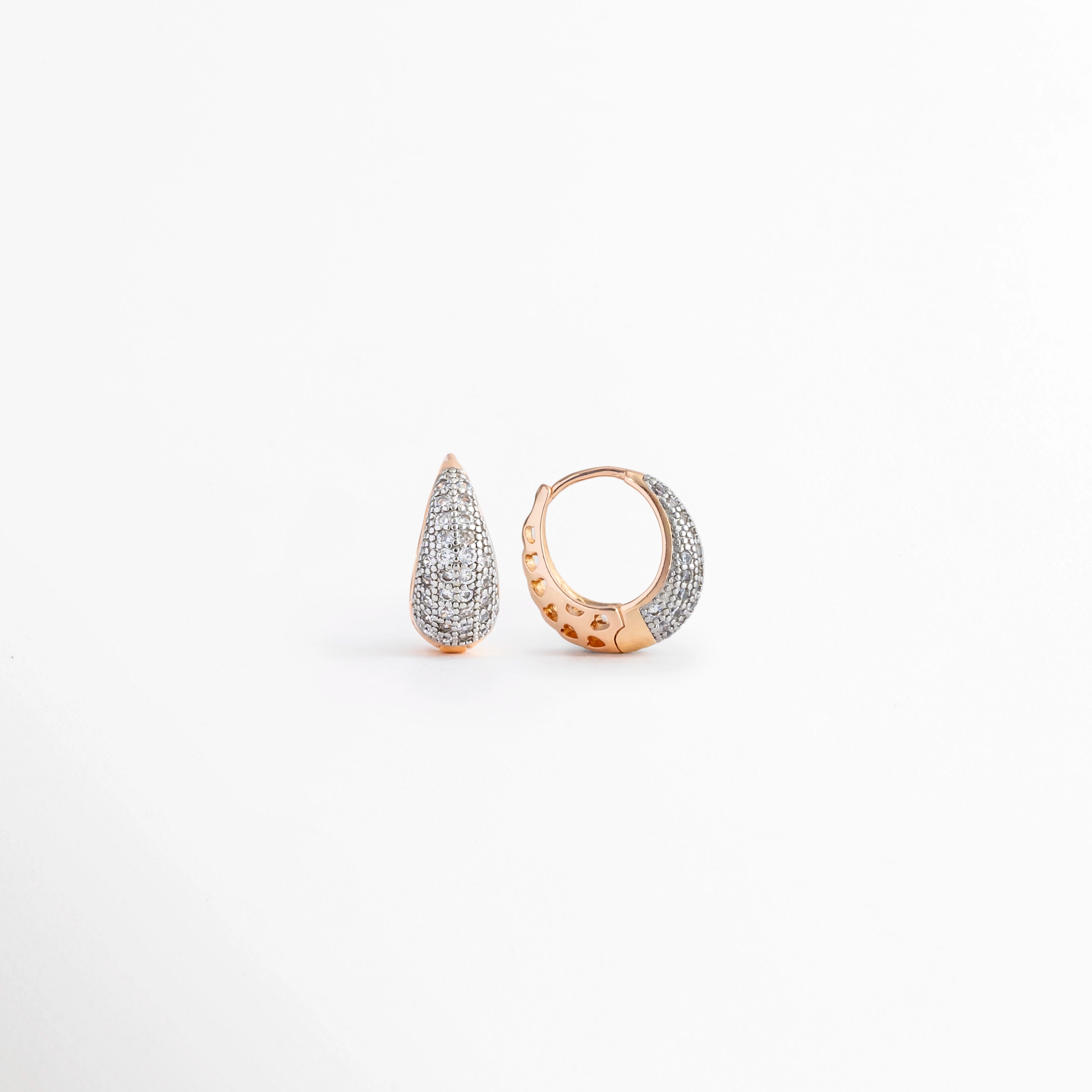 Vista en ángulo de los Aretes Zarya Golden Hoops mostrando el perfil y el brillo de las zirconias, Perspectiva de los Aretes Zarya Golden Hoops con acabado en Oro 18K y diseño tipo huggie, Aretes Zarya Golden Hoops fotografiados de perfil resaltando las zirconias incrustadas, Vista diagonal de los Aretes Zarya Golden Hoops elaborados en cobre con recubrimiento en Oro 18K, Aretes Zarya Golden Hoops en perspectiva mostrando su diseño elegante y acabado brillante.