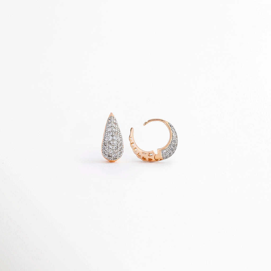 Vista lateral de los Aretes Zarya Golden Hoops mostrando el cierre tipo bisagra y el perfil del aro, Perfil de los Aretes Zarya Golden Hoops con acabado en Oro 18K y zirconias brillantes, Aretes Zarya Golden Hoops en vista lateral destacando el grosor del aro y el sistema de cierre, Detalle lateral de los Aretes Zarya Golden Hoops elaborados en cobre con incrustaciones de zirconias, Vista de costado de los Aretes Zarya Golden Hoops con diseño tipo huggie y acabado dorado.