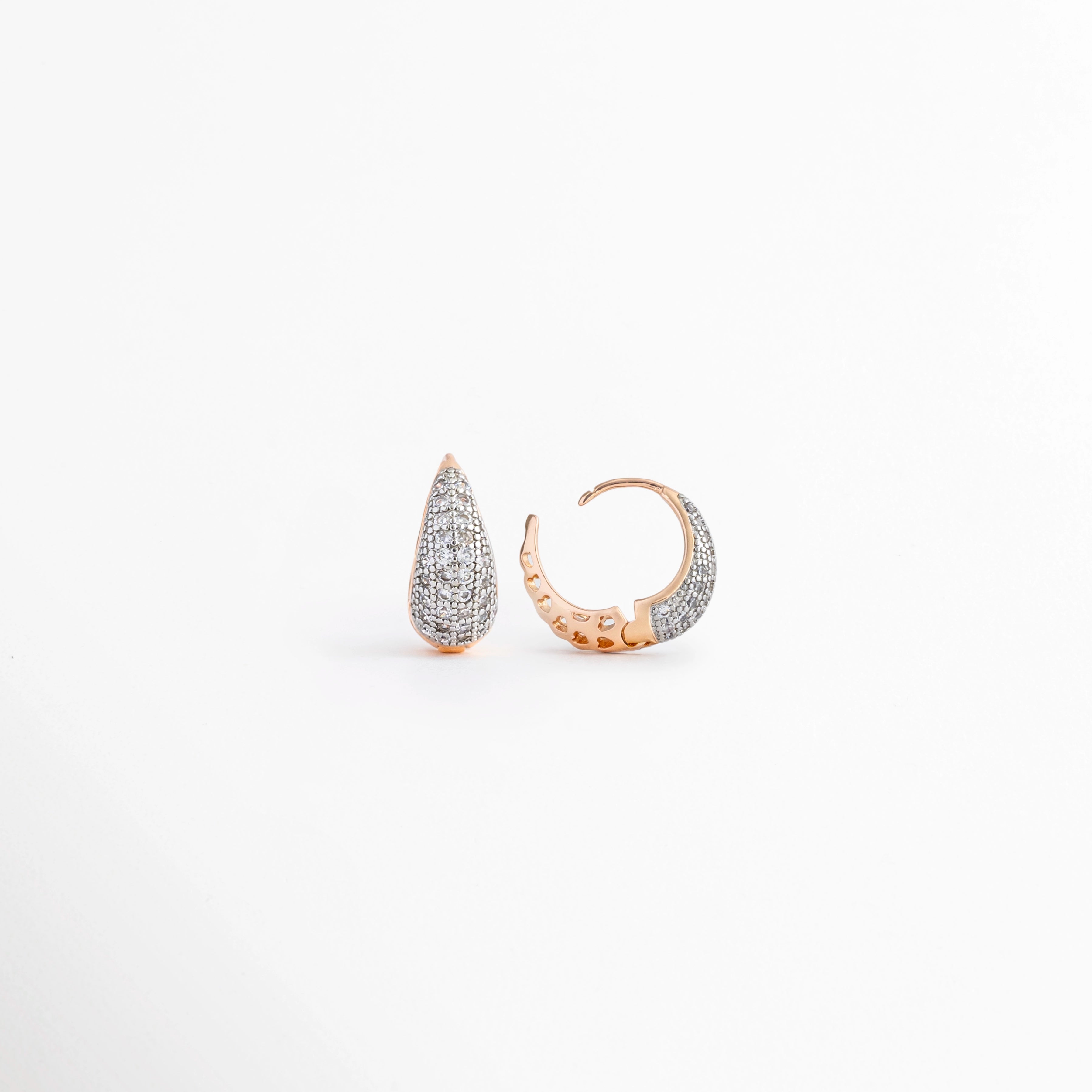 Vista lateral de los Aretes Zarya Golden Hoops mostrando el cierre tipo bisagra y el perfil del aro, Perfil de los Aretes Zarya Golden Hoops con acabado en Oro 18K y zirconias brillantes, Aretes Zarya Golden Hoops en vista lateral destacando el grosor del aro y el sistema de cierre, Detalle lateral de los Aretes Zarya Golden Hoops elaborados en cobre con incrustaciones de zirconias, Vista de costado de los Aretes Zarya Golden Hoops con diseño tipo huggie y acabado dorado.