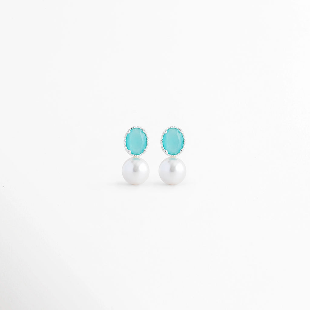 Aretes Boreal Blue de plata con acabado en Oro Blanco 18K, piedra preciosa marina azul y perla blanca sobre fondo blanco, Vista frontal de los Aretes Boreal Blue con piedra azul marina, perla blanca y diseño elegante de plata, Aretes Boreal Blue con piedra preciosa marina ovalada y perla blanca, elaborados en plata con recubrimiento de Oro Blanco 18K, Par de Aretes Boreal Blue con diseño minimalista, piedra azul y perla blanca en acabado de Oro Blanco 18K, Aretes de plata Boreal Blue con piedra azul marina
