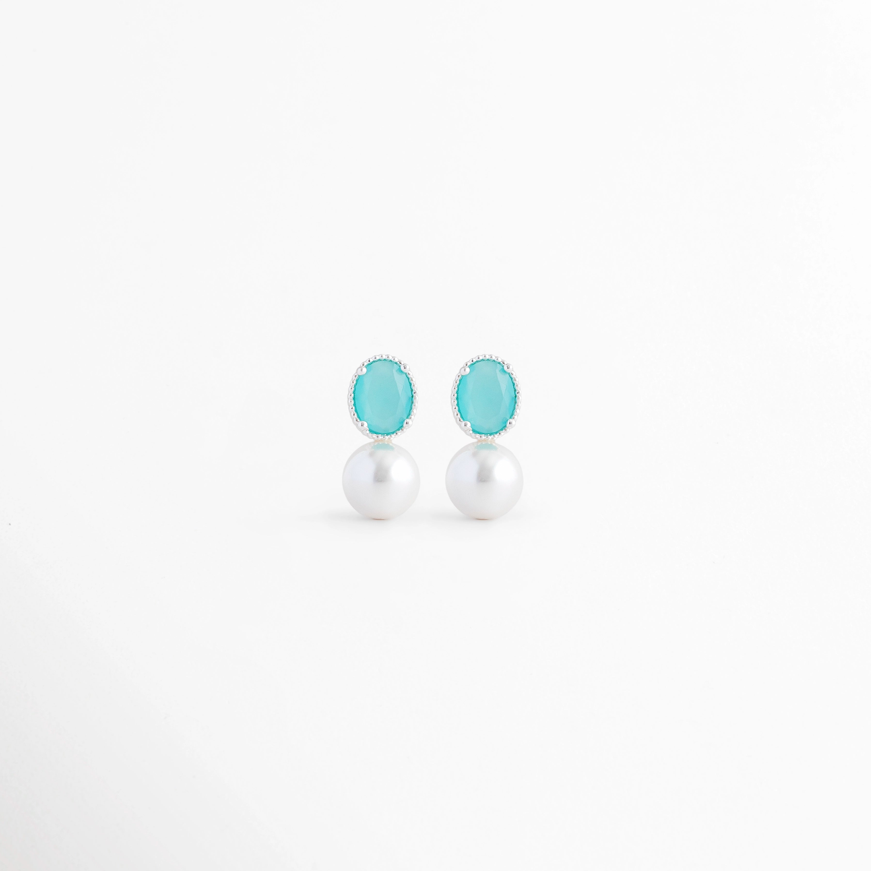 Aretes Boreal Blue de plata con acabado en Oro Blanco 18K, piedra preciosa marina azul y perla blanca sobre fondo blanco, Vista frontal de los Aretes Boreal Blue con piedra azul marina, perla blanca y diseño elegante de plata, Aretes Boreal Blue con piedra preciosa marina ovalada y perla blanca, elaborados en plata con recubrimiento de Oro Blanco 18K, Par de Aretes Boreal Blue con diseño minimalista, piedra azul y perla blanca en acabado de Oro Blanco 18K, Aretes de plata Boreal Blue con piedra azul marina