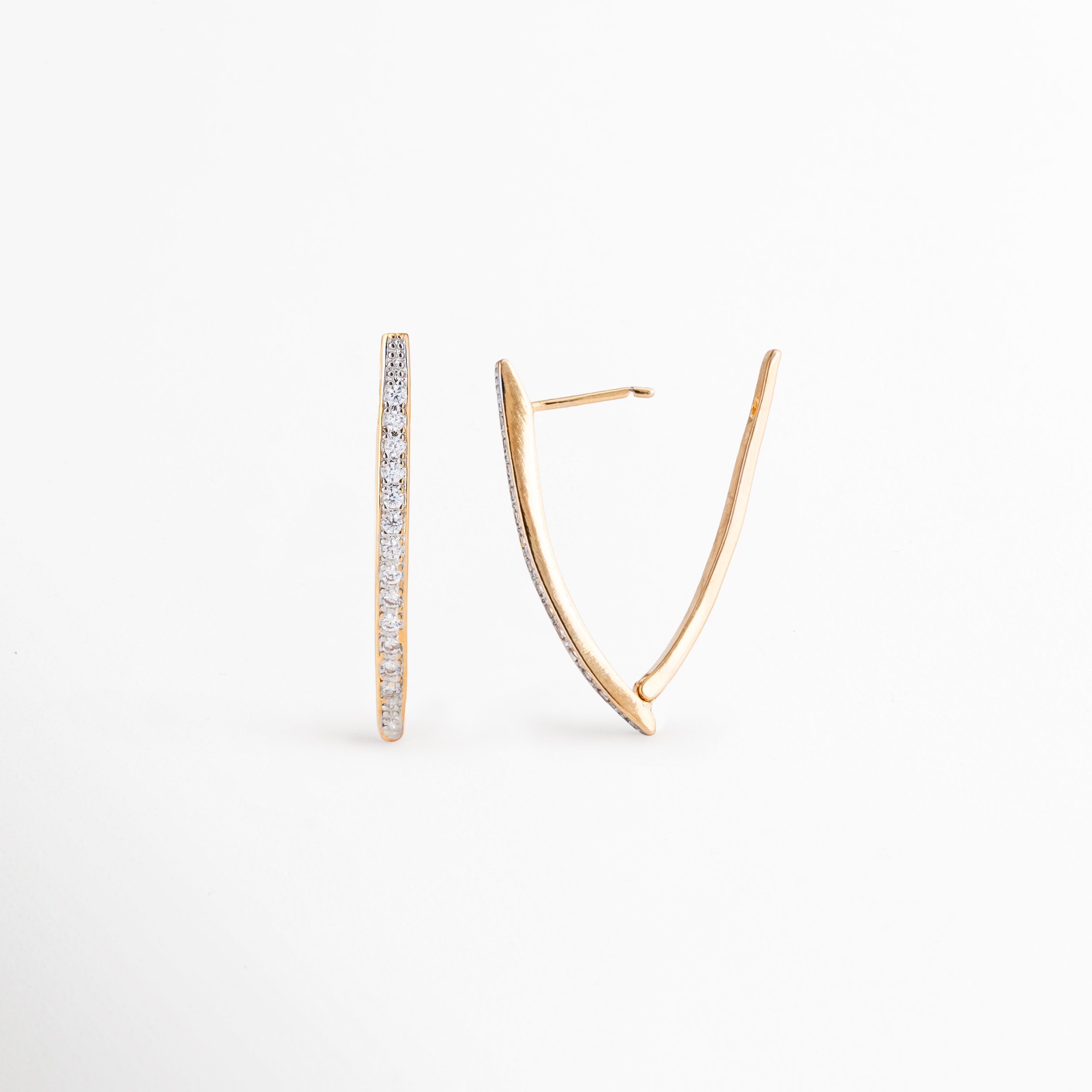 Aretes Regina desde ángulo lateral mostrando su diseño alargado, Detalle de aretes dorados con zirconias y acabado brillante, Vista angular de aretes modernos que enmarcan el rostro, Aretes largos con diseño geométrico y brillo elegante, Detalle de aretes statement dorados con zirconias.
