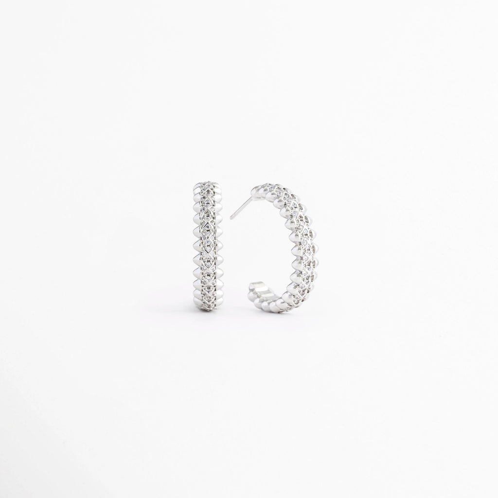 Vista en ángulo de los Aretes Silver Azira mostrando el perfil y el broche tipo poste, Perspectiva de los Aretes Silver Azira con acabado en Oro Blanco y zirconias brillantes, Aretes Silver Azira fotografiados de perfil resaltando su diseño lineal, Vista diagonal de los Aretes Silver Azira elaborados en aleación metálica con acabado en Oro Blanco, Aretes Silver Azira en perspectiva mostrando su estructura delgada y elegante.