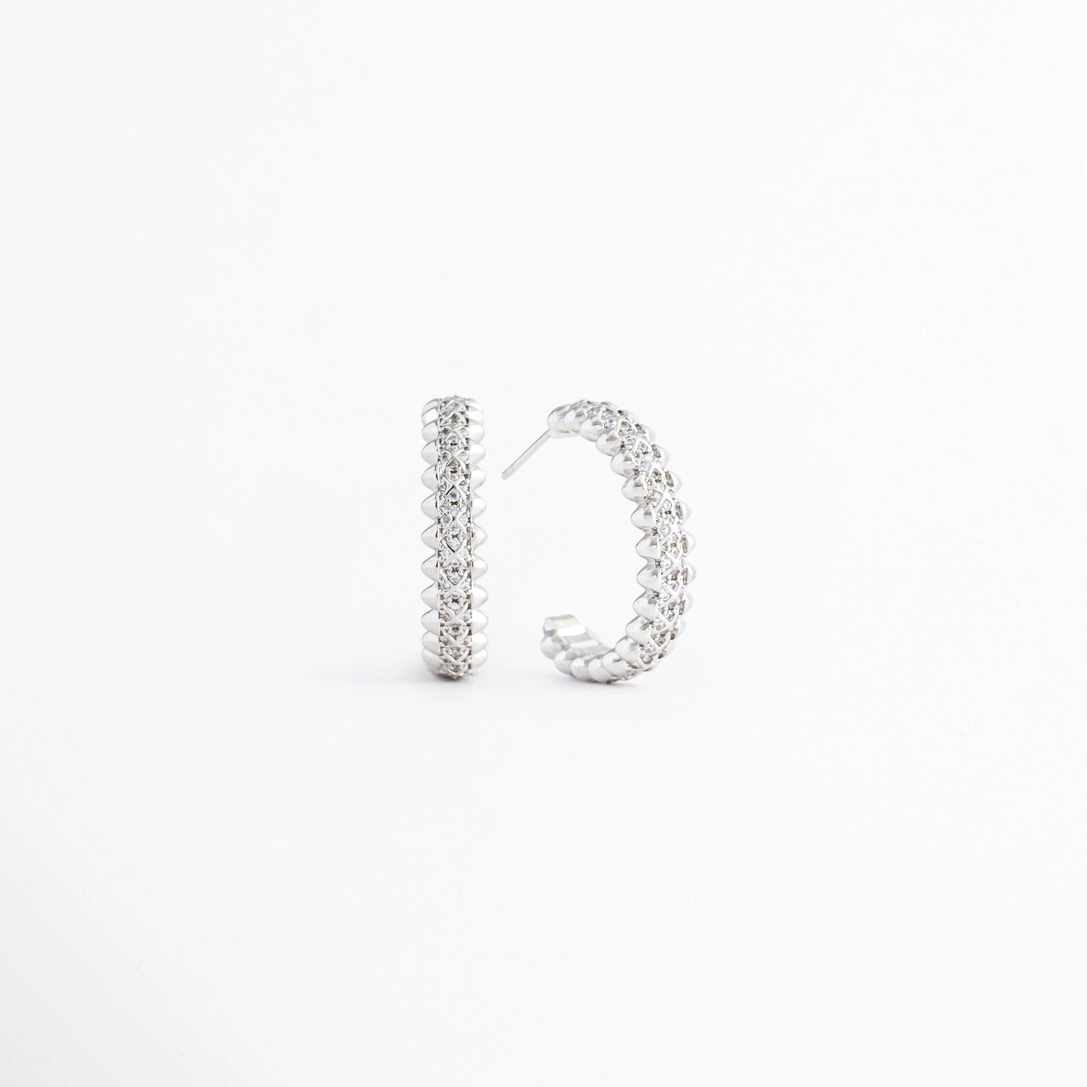 Vista en ángulo de los Aretes Silver Azira mostrando el perfil y el broche tipo poste, Perspectiva de los Aretes Silver Azira con acabado en Oro Blanco y zirconias brillantes, Aretes Silver Azira fotografiados de perfil resaltando su diseño lineal, Vista diagonal de los Aretes Silver Azira elaborados en aleación metálica con acabado en Oro Blanco, Aretes Silver Azira en perspectiva mostrando su estructura delgada y elegante.