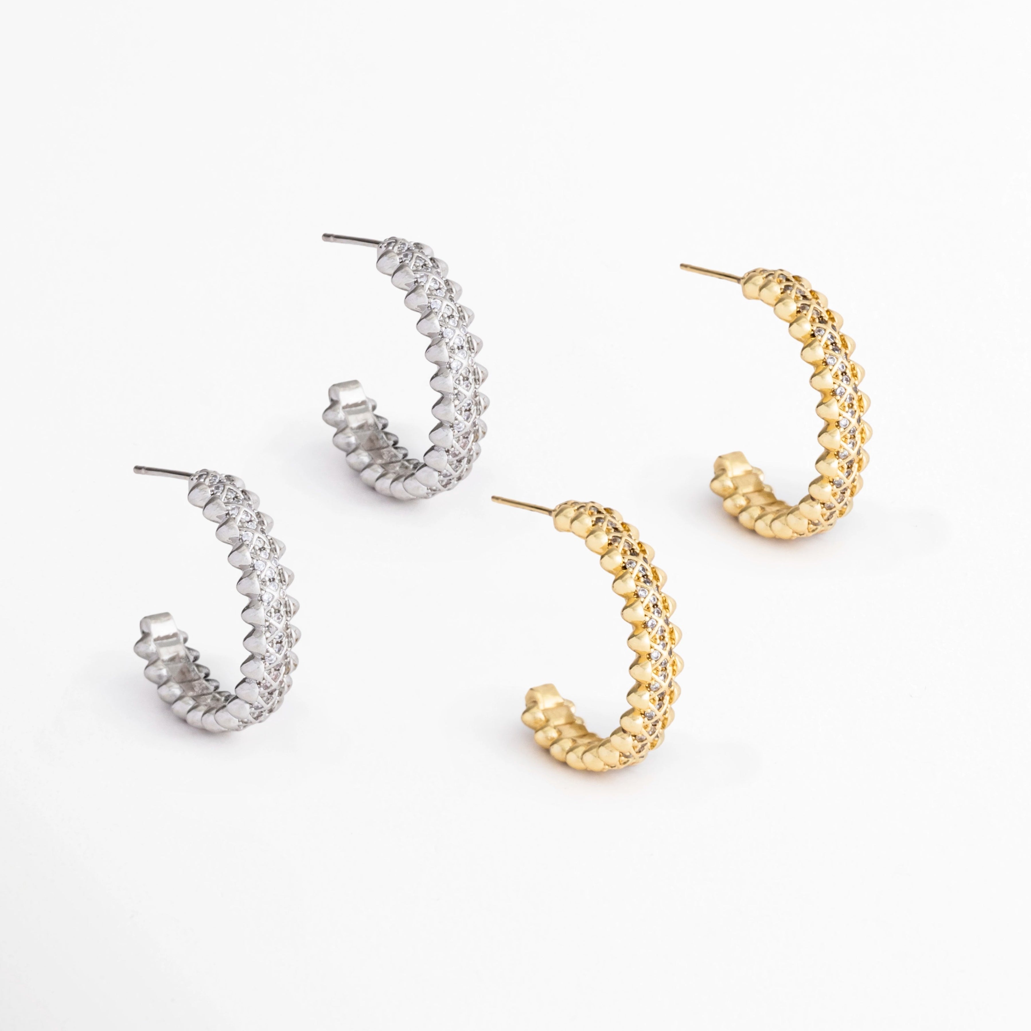 Aretes Azira disponibles en acabados Oro Blanco y Oro con incrustaciones de zirconias, Comparativa de los Aretes Azira en color plateado y dorado sobre fondo blanco, Variantes de color de los Aretes Azira con diseño lineal y zirconias, Aretes Azira mostrando las versiones plateada y dorada del mismo diseño contemporáneo, Vista comparativa de los Aretes Azira disponibles en acabado plateado y dorado.