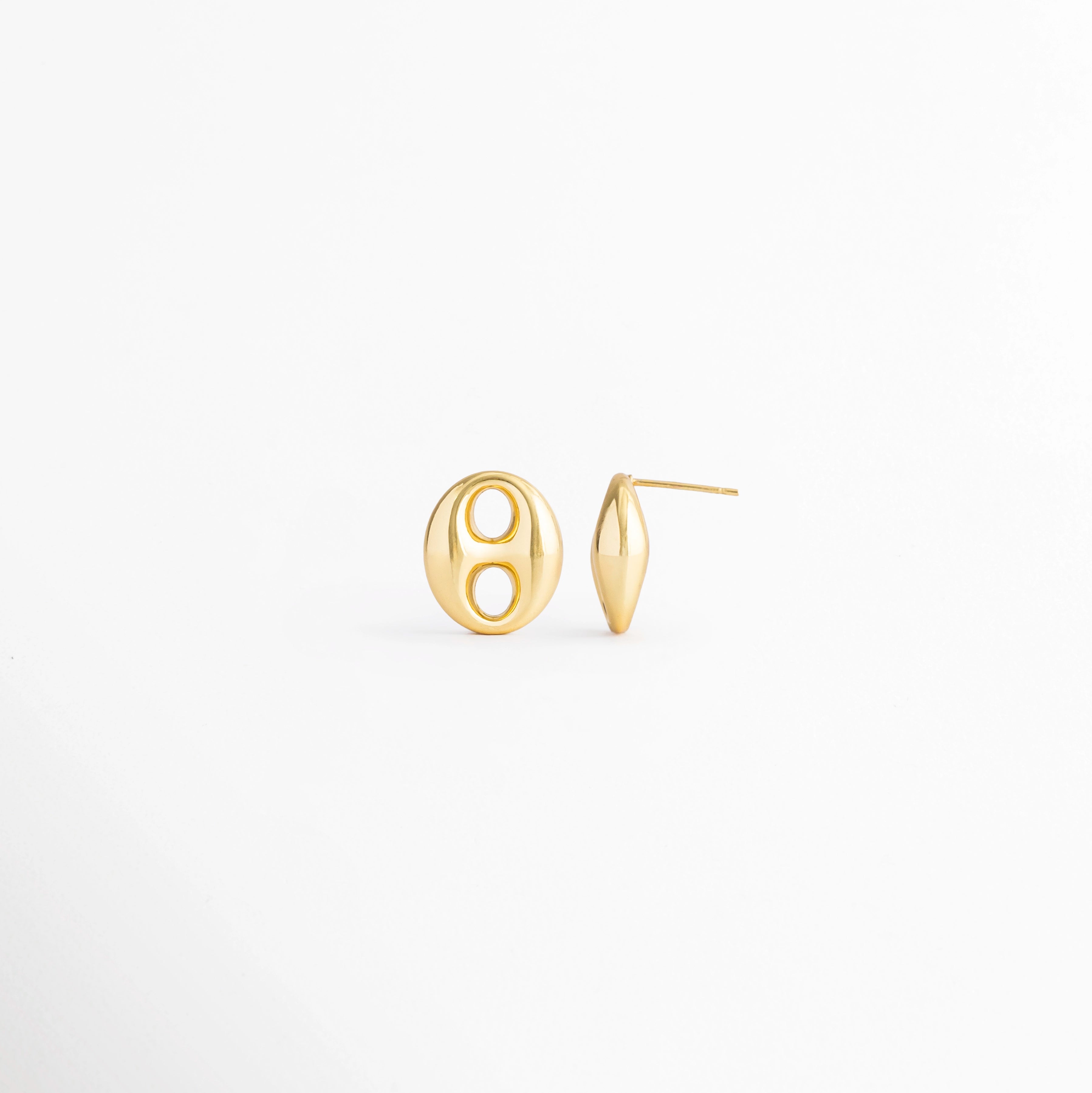 Vista en ángulo de los Aretes Sahra Golden Studs mostrando el perfil y el broche tipo poste, Perspectiva de los Aretes Sahra Golden Studs con acabado en Oro 18K y diseño geométrico ovalado, Aretes Sahra Golden Studs fotografiados de perfil resaltando el acabado dorado brillante, Vista diagonal de los Aretes Sahra Golden Studs elaborados en acero inoxidable con recubrimiento en Oro 18K, Aretes Sahra Golden Studs en perspectiva mostrando su estructura y diseño minimalista.