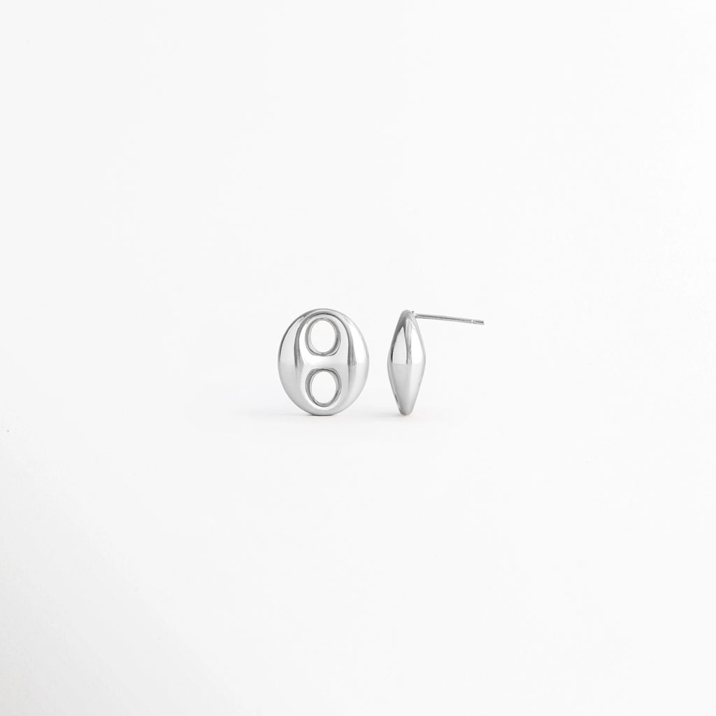 Vista en ángulo de los Aretes Sahra Silver Studs mostrando el perfil y el broche tipo poste, Perspectiva de los Aretes Sahra Silver Studs con acabado en Oro Blanco 18K y diseño geométrico, Aretes Sahra Silver Studs fotografiados de perfil resaltando su acabado plateado brillante, Vista diagonal de los Aretes Sahra Silver Studs elaborados en acero inoxidable con recubrimiento en Oro Blanco 18K, Aretes Sahra Silver Studs en perspectiva mostrando su estructura y diseño minimalista.