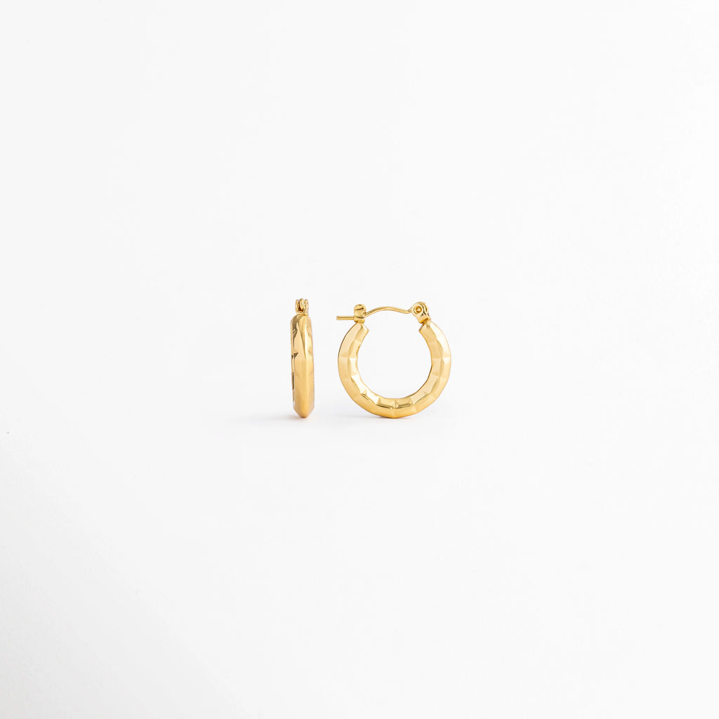 Aretes Doré Hoops de acero inoxidable con recubrimiento en Oro 18K y diseño clásico tipo huggie sobre fondo blanco, Vista frontal de los Aretes Doré Hoops con acabado brillante en Oro 18K y diseño de aro pequeño, Aretes Doré Hoops con diseño minimalista de aro redondo y acabado dorado, Par de Aretes Doré Hoops elaborados en acero inoxidable con acabado en Oro 18K, Aretes Doré Hoops con diseño elegante de aro liso y acabado dorado brillante.