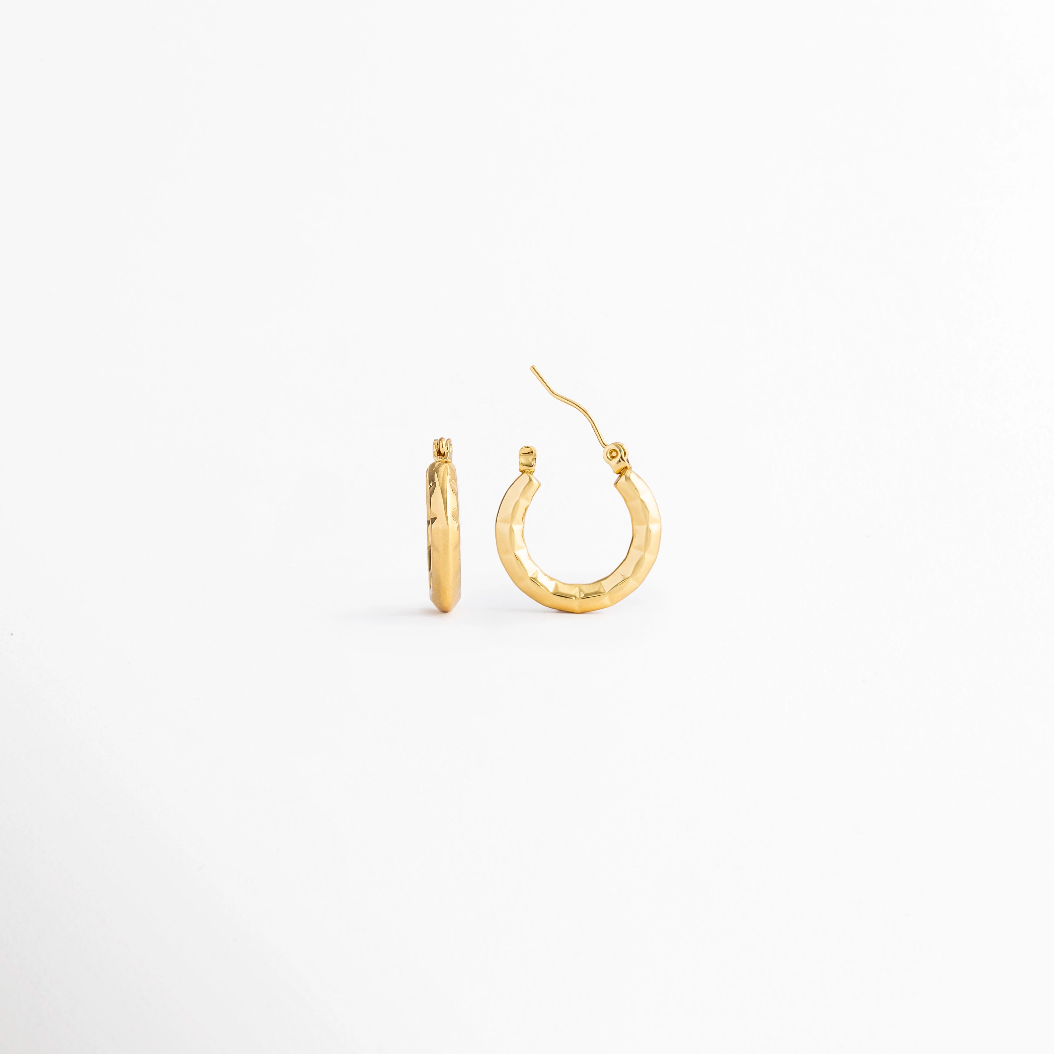 Vista lateral de los Aretes Doré Hoops mostrando el perfil del aro y el cierre tipo bisagra, Perfil de los Aretes Doré Hoops con acabado en Oro 18K y diseño minimalista, Aretes Doré Hoops en vista lateral destacando el grosor del aro y su acabado brillante, Detalle lateral de los Aretes Doré Hoops elaborados en acero inoxidable con recubrimiento en Oro 18K, Vista de costado de los Aretes Doré Hoops con diseño clásico de aro pequeño.
