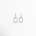 Aretes Silver Oria de cobre con recubrimiento en Oro Blanco 14K e incrustación de zirconia sobre fondo blanco, Vista frontal de los Aretes Silver Oria con diseño rectangular y zirconia en acabado de Oro Blanco 14K, Aretes Silver Oria con diseño geométrico de eslabón rectangular y zirconia brillante, Par de Aretes Silver Oria con acabado plateado y diseño minimalista para mujer, Aretes Silver Oria con forma rectangular y acabado en Oro Blanco 14K.