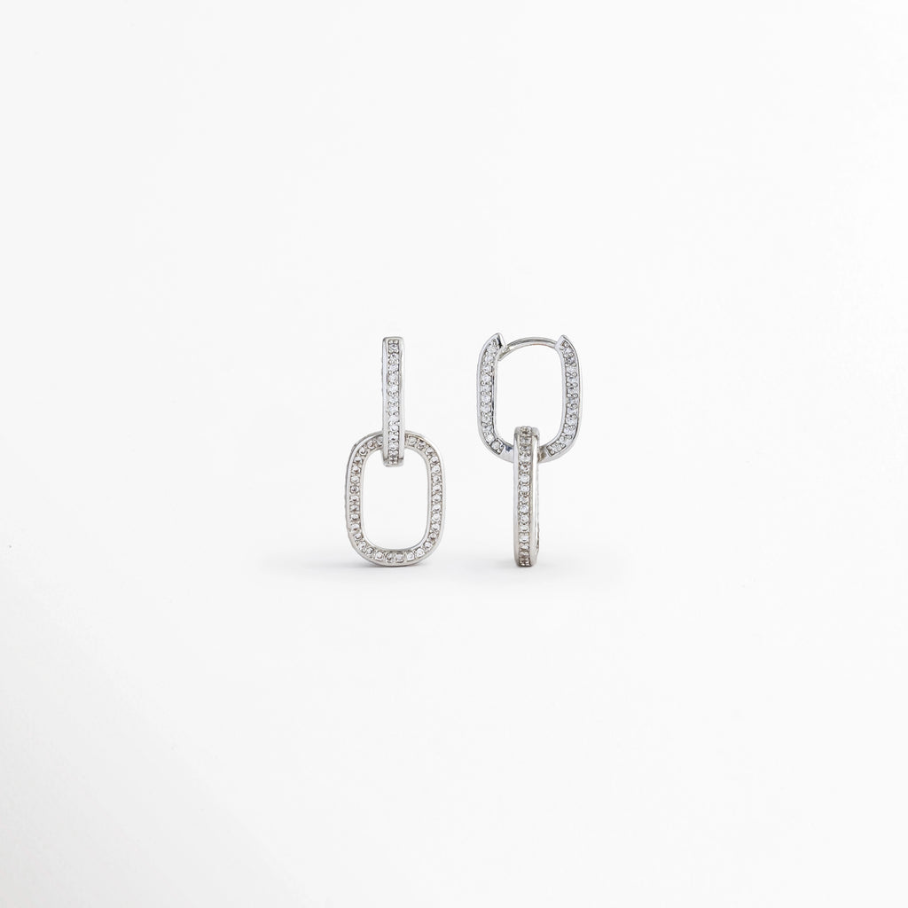 Vista posterior de los Aretes Silver Oria mostrando el broche tipo poste y el diseño rectangular, Parte trasera de los Aretes Silver Oria con cierre tipo poste y acabado en Oro Blanco 14K, Aretes Silver Oria en vista posterior destacando la estructura del broche y el diseño geométrico, Detalle de la parte posterior de los Aretes Silver Oria elaborados en cobre con acabado plateado, Vista trasera de los Aretes Silver Oria mostrando el sistema de cierre tipo poste.
