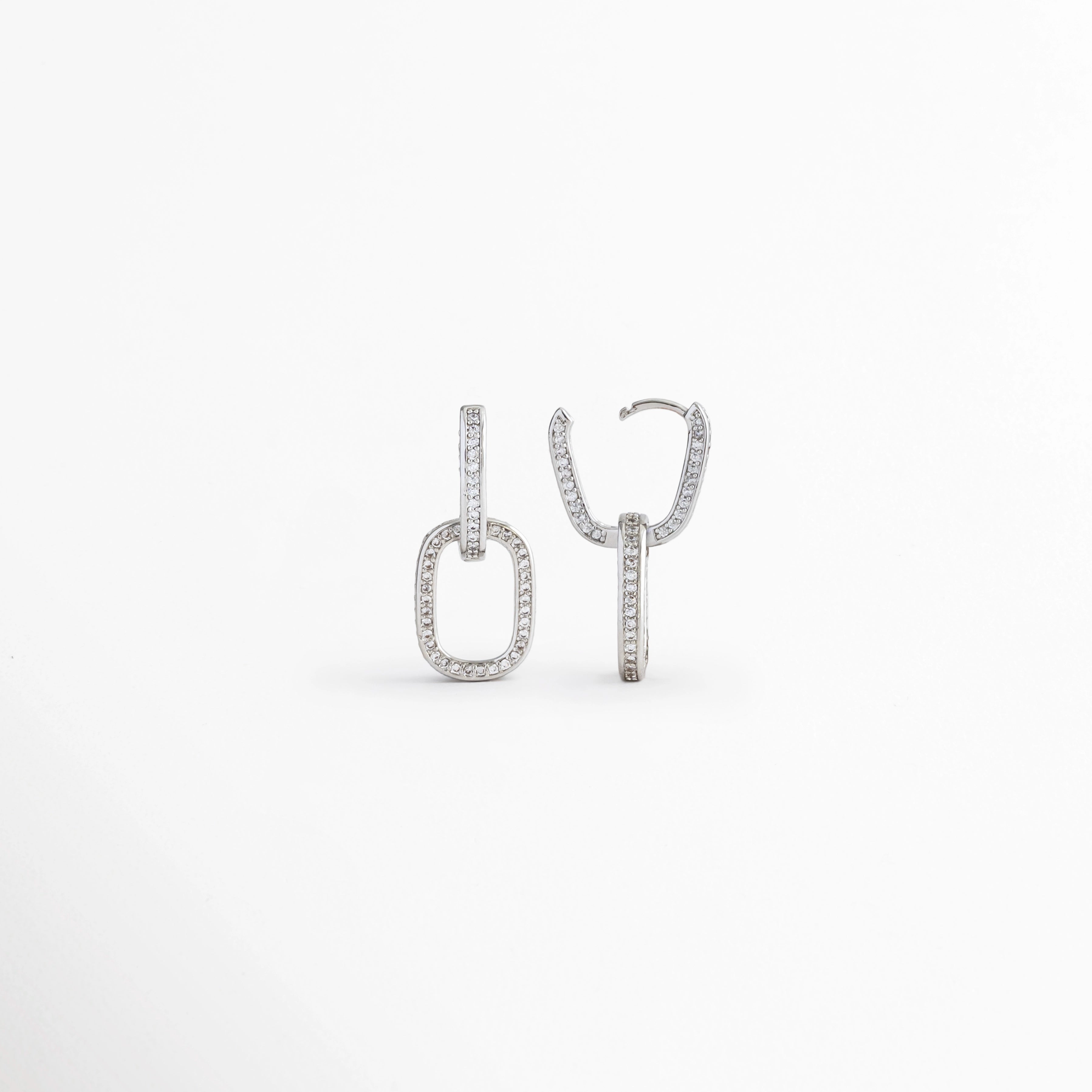 Vista lateral de los Aretes Silver Oria mostrando el perfil del diseño rectangular y el broche, Perfil de los Aretes Silver Oria con acabado en Oro Blanco 14K y zirconia incrustada, Aretes Silver Oria en vista lateral destacando el grosor de la pieza y el sistema de cierre, Detalle lateral de los Aretes Silver Oria elaborados en cobre con recubrimiento en Oro Blanco 14K, Vista de costado de los Aretes Silver Oria con diseño geométrico elegante y zirconia.