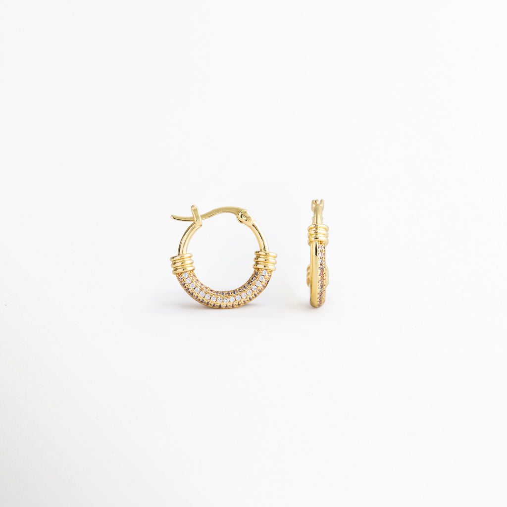 Vista lateral de los Aretes Lotus Hoops con zirconias incrustadas, Perfil de arracadas doradas con acabado brillante y diseño moderno, Detalle lateral de aretes tipo hoop con cierre seguro y zirconias, Aretes dorados para mujer con estructura ligera y elegante, Vista de perfil de Lotus Hoops con detalles de zirconia y acabado refinado.