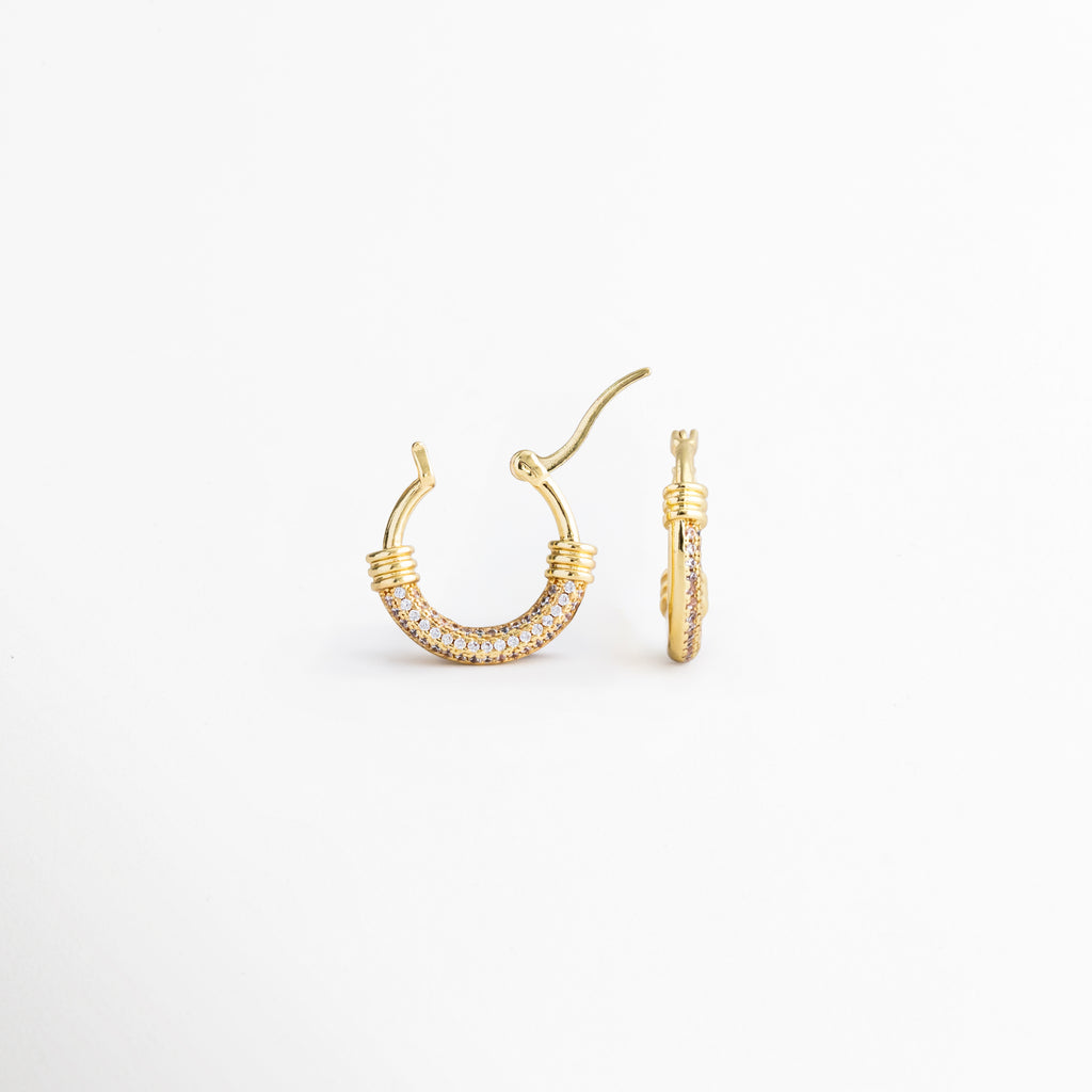 Detalle de los Aretes Lotus Hoops con incrustaciones de zirconia brillante, Vista cercana de arracadas doradas con diseño sofisticado y femenino, Aretes tipo hoop enchapados en oro con detalles luminosos de zirconia, Lotus Hoops con acabado dorado y estética moderna de inspiración minimalista, Detalle de aretes elegantes para mujer con brillo sutil y versátil.