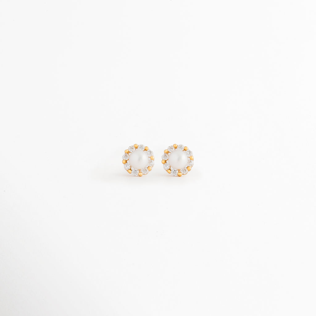 Aretes Zerina Golden Studs de Plata de Ley 925 con recubrimiento en Oro 14K y zirconia brillante sobre fondo blanco, Vista frontal de los Aretes Zerina Golden Studs con zirconia central rodeada de un delicado halo brillante, Aretes Zerina Golden Studs con diseño redondo, zirconia y acabado en Oro 14K, Par de Aretes Zerina Golden Studs elaborados en Plata de Ley 925 con zirconia y acabado dorado, Aretes dorados Zerina Golden Studs con zirconia en diseño clásico y elegante.