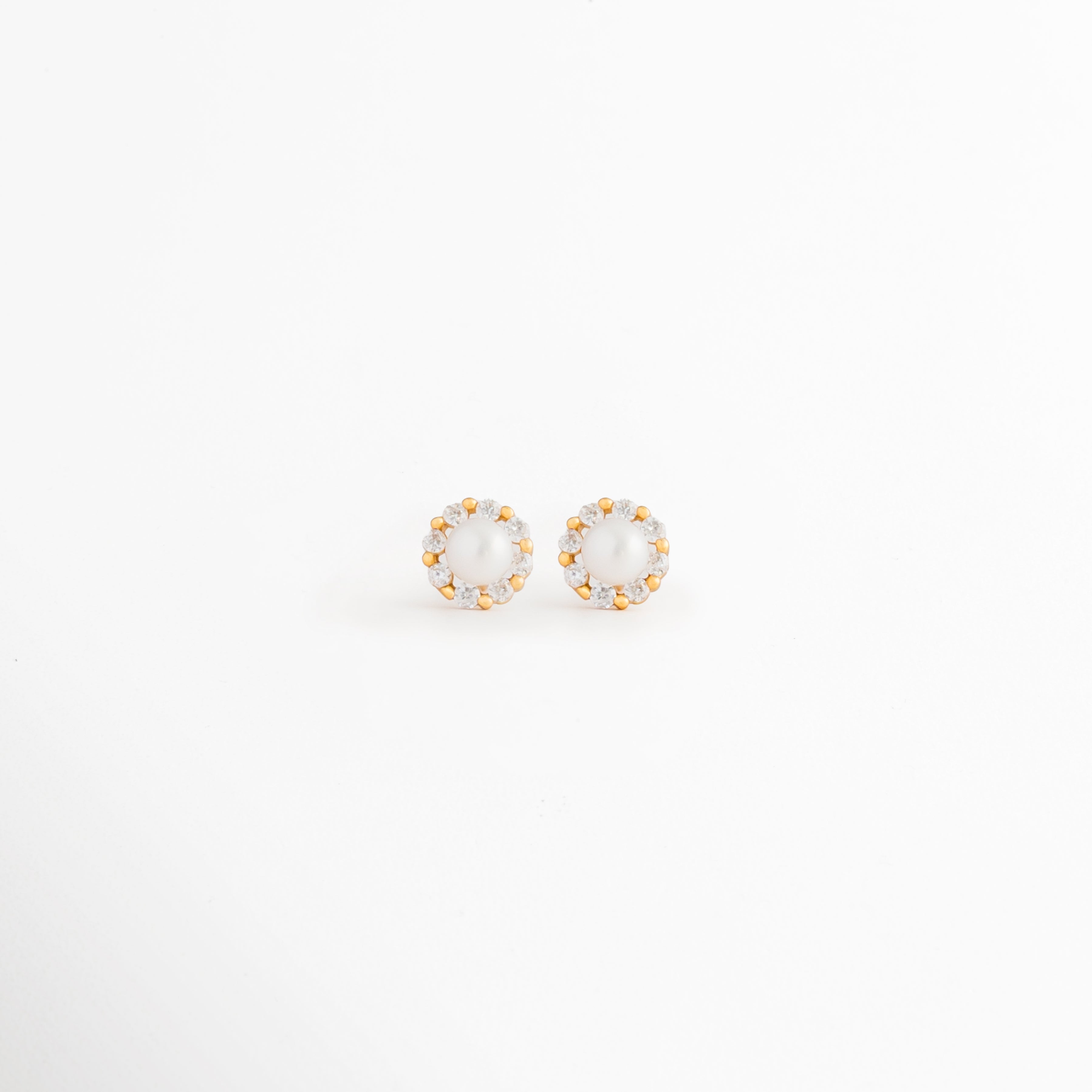 Aretes Zerina Golden Studs de Plata de Ley 925 con recubrimiento en Oro 14K y zirconia brillante sobre fondo blanco, Vista frontal de los Aretes Zerina Golden Studs con zirconia central rodeada de un delicado halo brillante, Aretes Zerina Golden Studs con diseño redondo, zirconia y acabado en Oro 14K, Par de Aretes Zerina Golden Studs elaborados en Plata de Ley 925 con zirconia y acabado dorado, Aretes dorados Zerina Golden Studs con zirconia en diseño clásico y elegante.