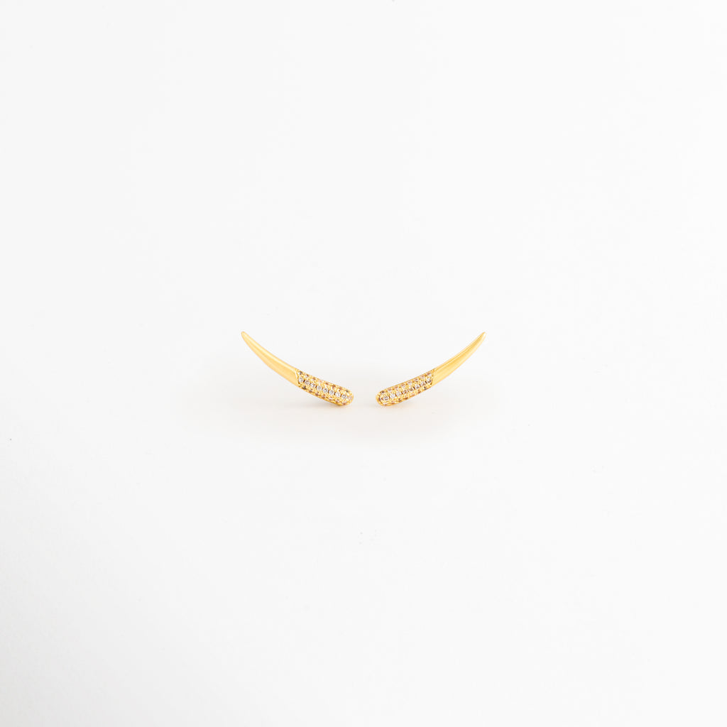 Aretes Golden Zerald de cobre con recubrimiento en Oro e incrustaciones de zirconias sobre fondo blanco, Vista frontal de los Aretes Golden Zerald con diseño curvo y zirconias brillantes, Aretes Golden Zerald con diseño minimalista curvo y acabado en Oro, Par de Aretes Golden Zerald con zirconias incrustadas y acabado dorado brillante, Aretes Golden Zerald con diseño elegante de líneas curvas y zirconias.