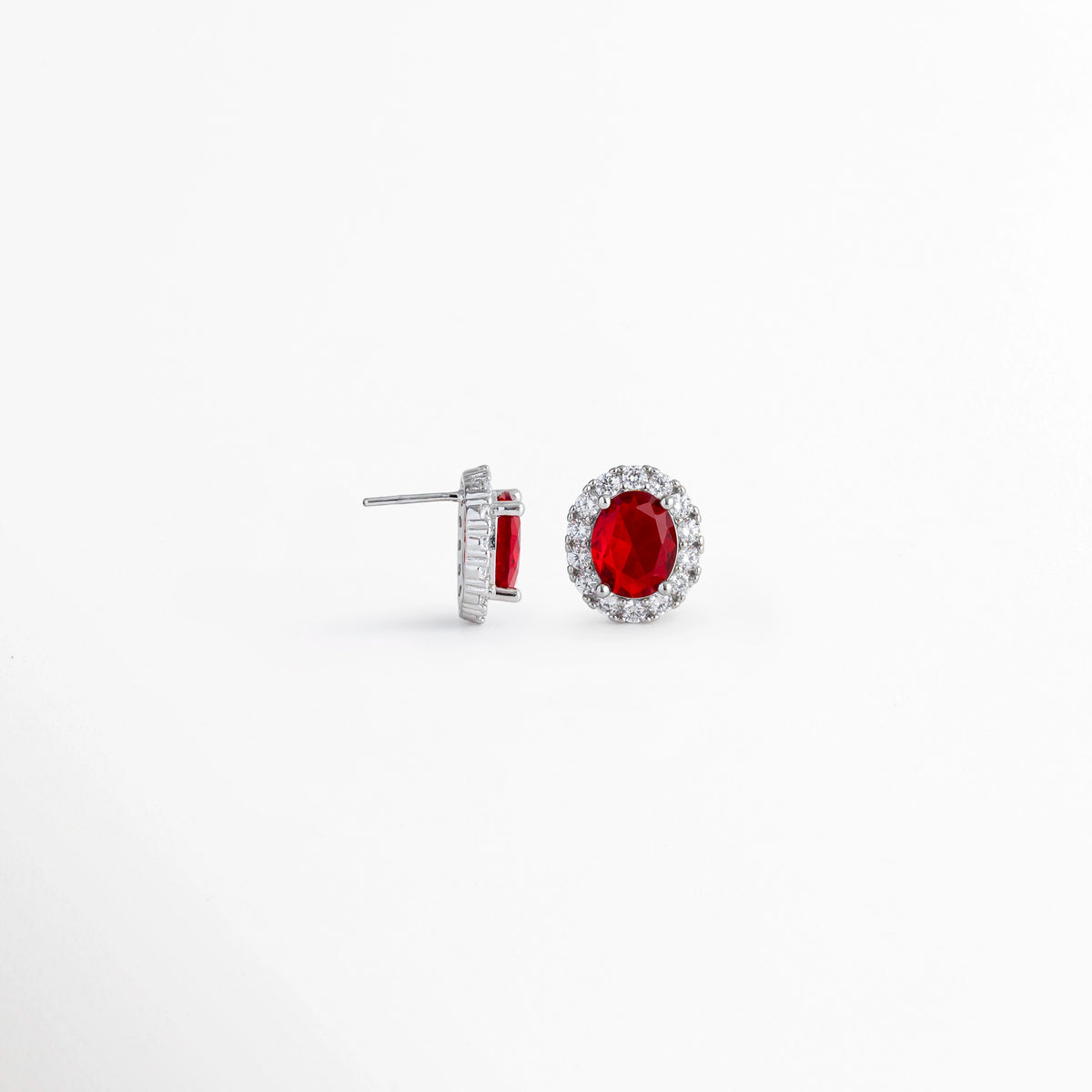 Vista lateral de los aretes Crimson Studs mostrando el poste de Plata Ley 925 para oreja perforada, Acercamiento de perfil a la estructura del broquel platinado y la altura del engaste de la gema carmesí, Detalle del sistema de ajuste por poste posterior y mariposa de los studs con pedrería roja, Muestra de la confección en plata ley 925 con recubrimiento platinado de alta durabilidad.