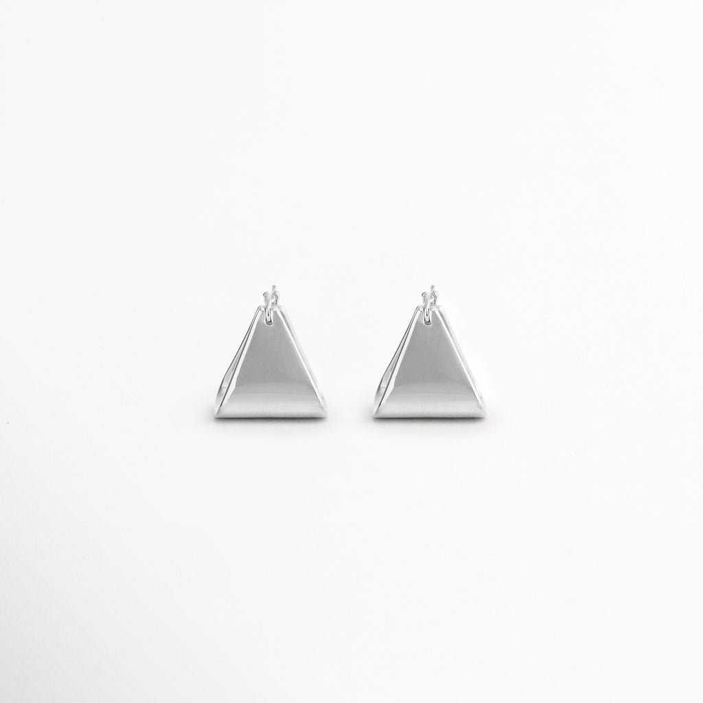 Aretes Silver Corot de diseño triangular minimalista en acabado oro blanco 18K, ideales para uso diario y ocasiones especiales, Par de aretes geométricos Silver Corot con forma de triángulo, elaborados en cobre con recubrimiento enchapado en oro blanco 18K, Aretes pequeños y ligeros Silver Corot con silueta triangular moderna y estilo minimalista atemporal, Aretes de triángulo plateado Silver Corot para mujer, diseño versátil que complementa looks casuales y elegantes, Pendientes minimalistas Silver Corot 