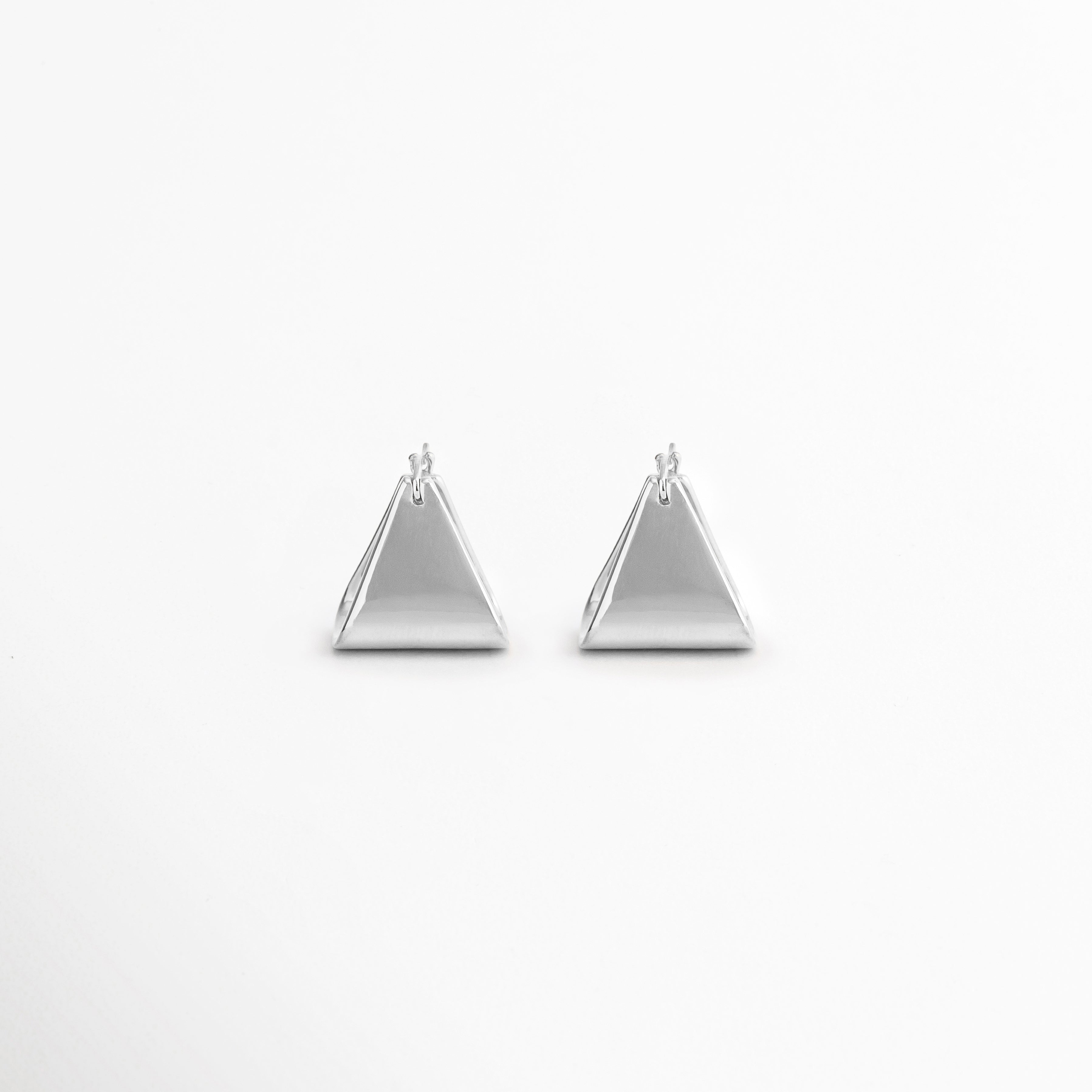 Aretes Silver Corot de diseño triangular minimalista en acabado oro blanco 18K, ideales para uso diario y ocasiones especiales, Par de aretes geométricos Silver Corot con forma de triángulo, elaborados en cobre con recubrimiento enchapado en oro blanco 18K, Aretes pequeños y ligeros Silver Corot con silueta triangular moderna y estilo minimalista atemporal, Aretes de triángulo plateado Silver Corot para mujer, diseño versátil que complementa looks casuales y elegantes, Pendientes minimalistas Silver Corot 