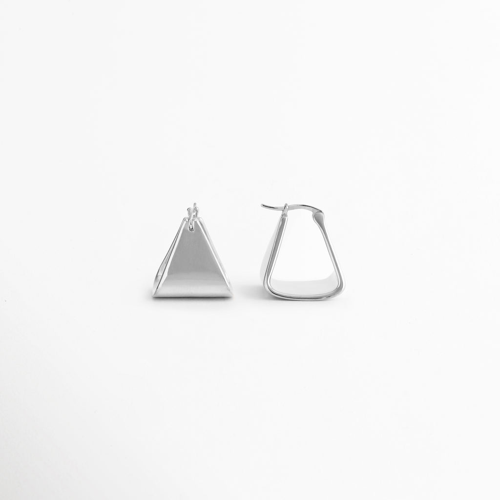 Vista lateral de los aretes Silver Corot que muestra su perfil delgado y estructura ligera para mayor comodidad, Aretes triangulares Silver Corot vistos de costado, destacando su diseño limpio y acabado pulido en oro blanco 18K, Perfil lateral de pendientes Silver Corot con forma geométrica moderna y detalles minimalistas, Vista de espesor y estructura de los aretes Silver Corot elaborados en cobre con recubrimiento de oro blanco 18K, Aretes minimalistas Silver Corot en perspectiva lateral