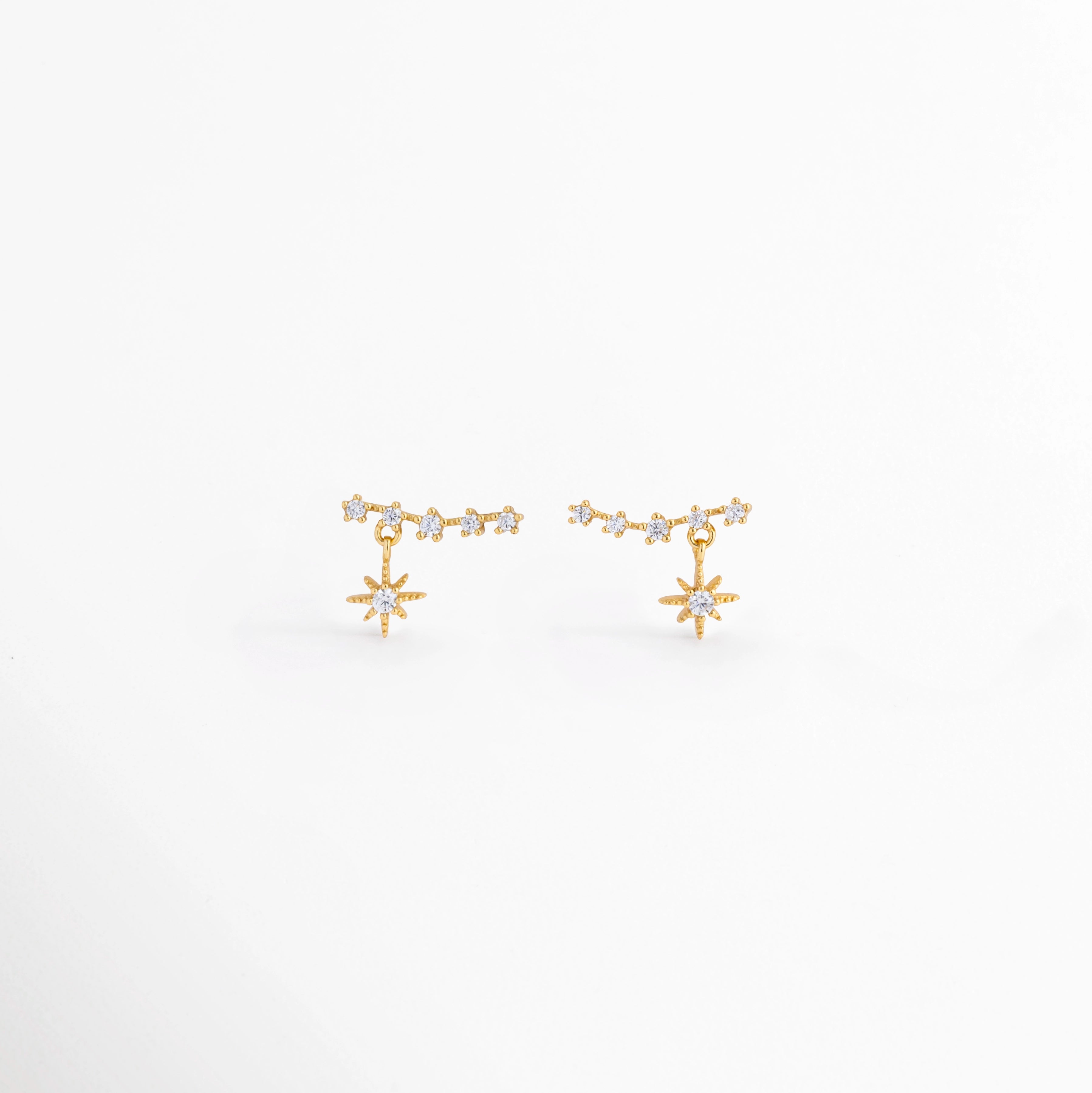 Aretes Morea de plata Ley 925 con recubrimiento en oro blanco 14K y zirconias, diseño colgante de estrella vista frontal,Pendientes Morea con estrella colgante y zirconias, elaborados en plata Ley 925 con acabado en oro blanco 14K, Vista frontal de aretes colgantes Morea con diseño de estrella y acabado en oro blanco 14K, Aretes pequeños de estrella con zirconias y base de plata Ley 925, vista frontal sobre fondo blanco. Par de aretes Morea con colgante de estrella de 1.1 cm, acabado en oro blanco 14K
