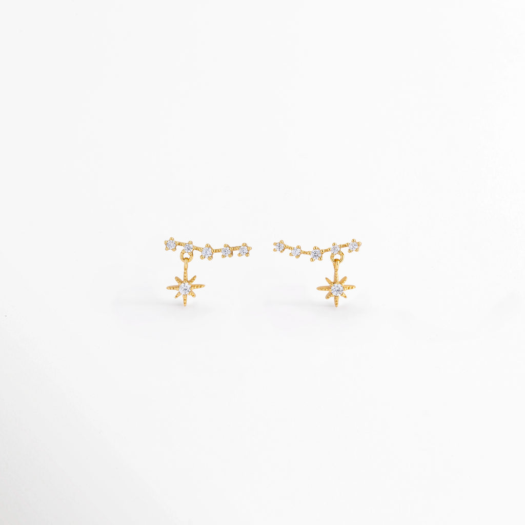 Aretes Morea de plata Ley 925 con recubrimiento en oro blanco 14K y zirconias, diseño colgante de estrella vista frontal,Pendientes Morea con estrella colgante y zirconias, elaborados en plata Ley 925 con acabado en oro blanco 14K, Vista frontal de aretes colgantes Morea con diseño de estrella y acabado en oro blanco 14K, Aretes pequeños de estrella con zirconias y base de plata Ley 925, vista frontal sobre fondo blanco. Par de aretes Morea con colgante de estrella de 1.1 cm, acabado en oro blanco 14K