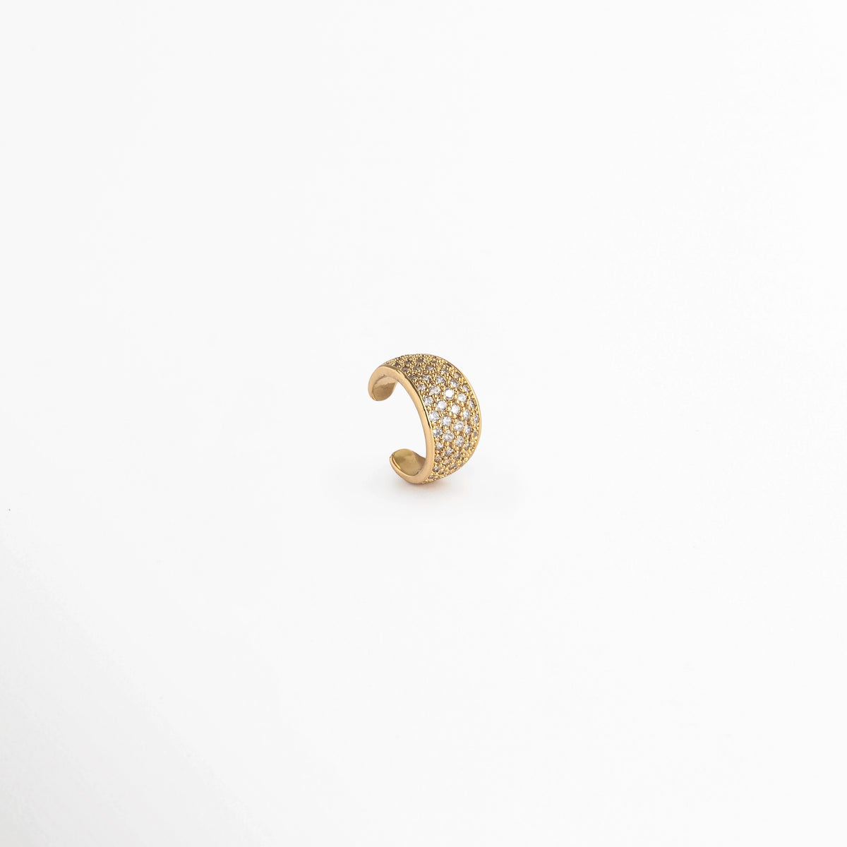 Vista lateral de perfil del Elara Golden Ear Cuff en posición vertical destacando el pulido dorado del interior y el reverso, Acercamiento al contorno curvo del earcuff de cartílago con frente de micro-circonias transparentes, Toma en ángulo que resalta el contraste entre la pedrería brillante y los bordes metálicos enchapados en oro, Muestra de la flexibilidad y firmeza de la pieza de 1.2 cm de largo para un ajuste seguro en la oreja
