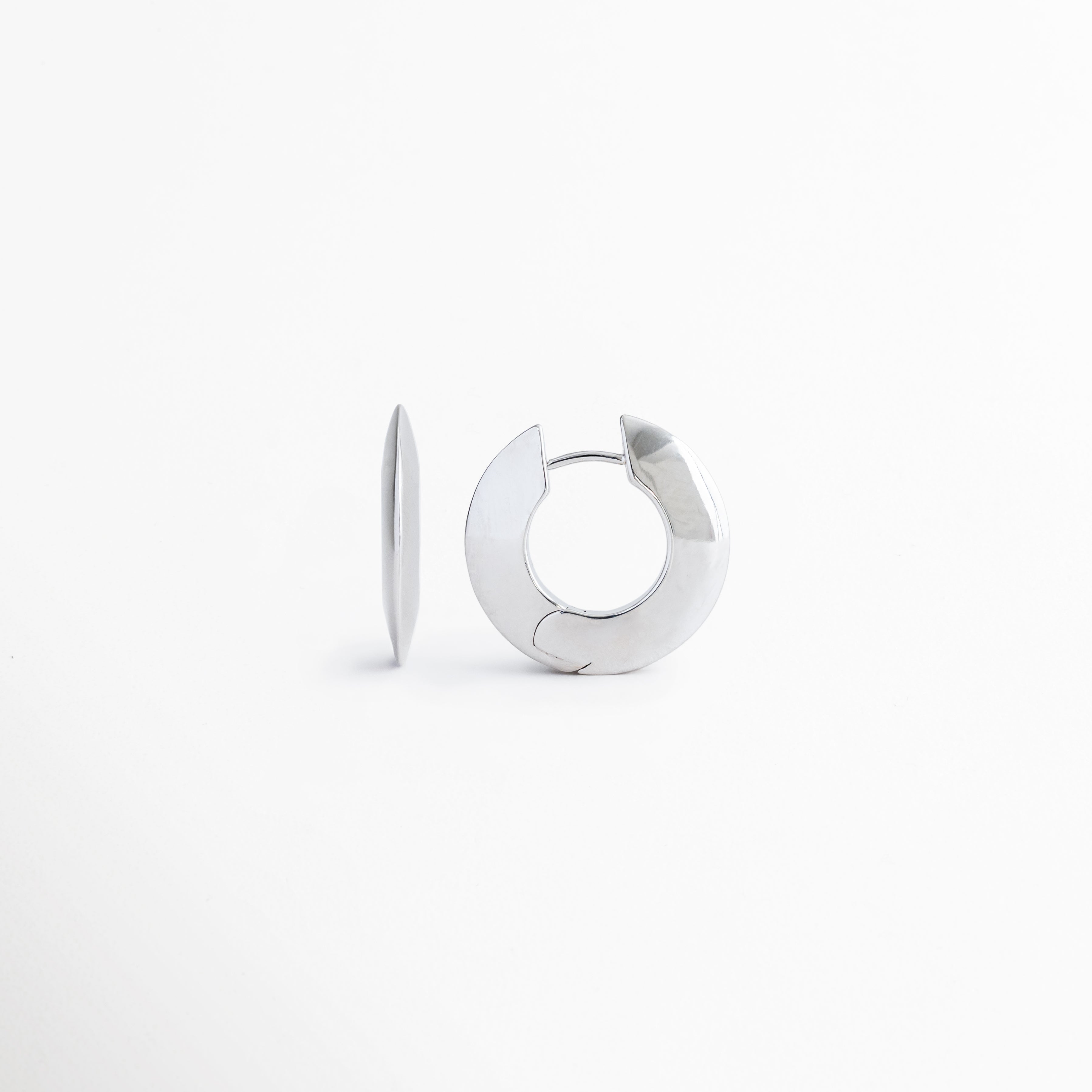 Vista lateral de los aretes Silver Maelis que resalta su perfil estilizado y diseño moderno tipo aro, Aretes Silver Maelis vistos de costado mostrando su estructura ligera y acabado brillante en oro blanco, Perfil lateral de pendientes geométricos Silver Maelis con líneas limpias y estética contemporánea, Detalle lateral de aretes tipo aro ovalado Silver Maelis elaborados en cobre con recubrimiento plateado, Perspectiva lateral de los aretes Silver Maelis destacando su diseño minimalista y elegante.