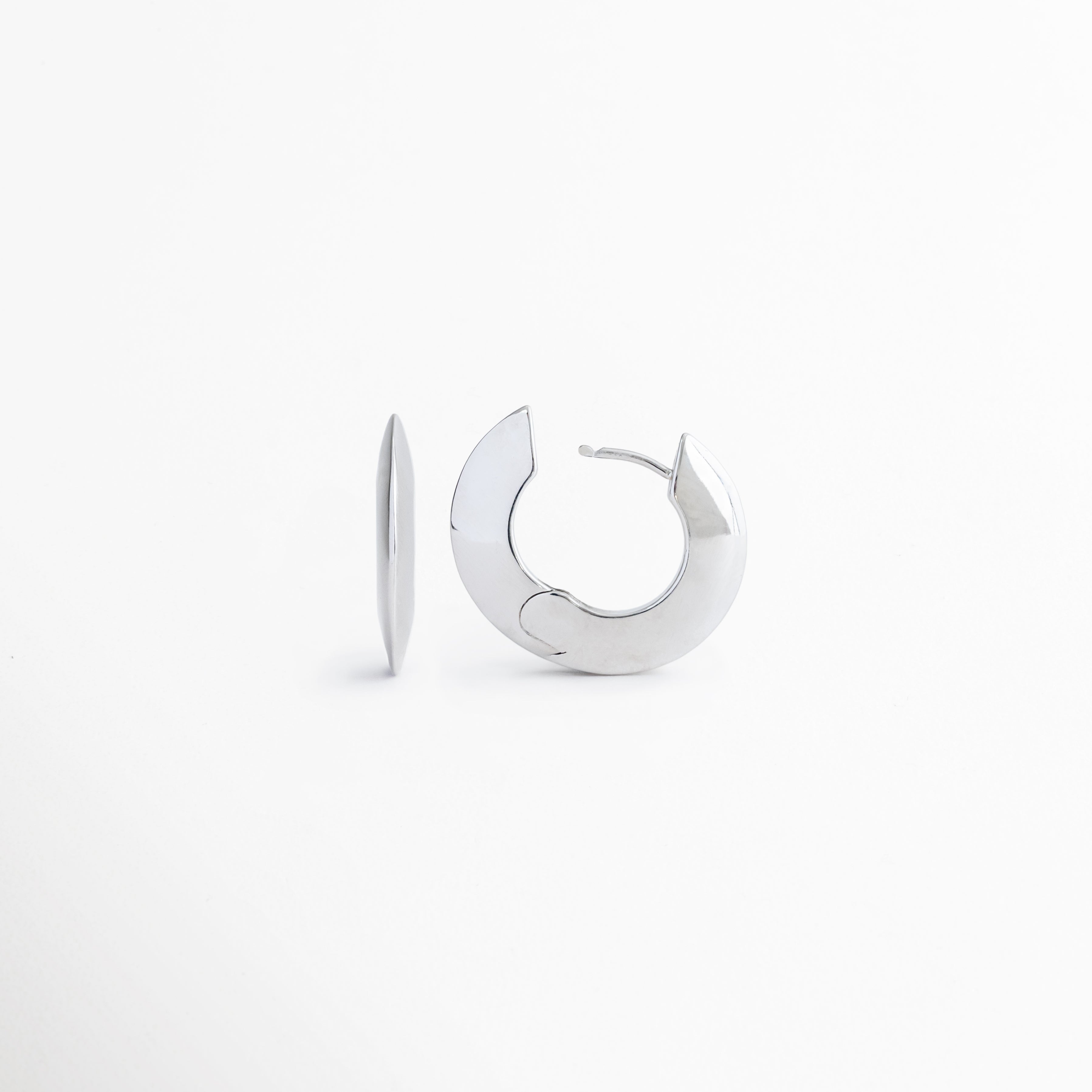 Vista inclinada de los aretes Silver Maelis que permite apreciar su forma ovalada y acabado brillante, Aretes tipo aro Silver Maelis en perspectiva frontal mostrando su diseño geométrico moderno y sofisticado, Detalle de pendientes Silver Maelis con silueta ovalada y acabado plateado de alto brillo, Aretes minimalistas Silver Maelis con diseño versátil y contemporáneo para cualquier ocasión, Vista complementaria de los aretes Silver Maelis destacando su estructura ligera y elegante.