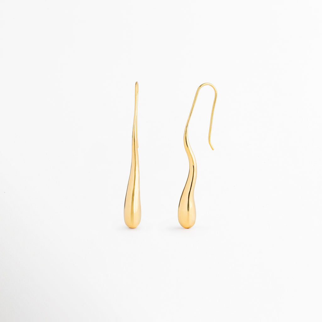 Vista lateral de los aretes Soline que muestra su perfil estilizado y diseño ligero de inspiración vintage, Aretes Soline vistos de costado destacando su elegante silueta alargada tipo lágrima, Perfil lateral de pendientes dorados Soline con acabado pulido en oro 18K y caída sofisticada, Detalle lateral de los aretes Soline elaborados en latón con diseño femenino y refinado, Aretes largos Soline en perspectiva lateral que resaltan su forma fluida y elegante movimiento.