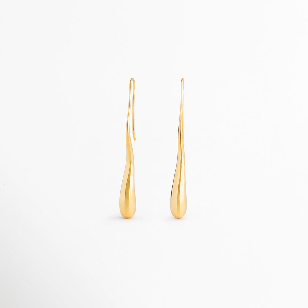 Vista posterior de los aretes Soline mostrando su estructura ligera y sistema de colocación cómodo, Parte trasera de los pendientes Soline con acabado dorado brillante y diseño estilizado, Detalle posterior de aretes largos tipo lágrima Soline elaborados en latón con recubrimiento en oro 18K, Aretes Soline vistos desde atrás destacando su construcción elegante y minimalista, Vista trasera de pendientes dorados Soline con diseño sofisticado para complementar cualquier ocasión especial.