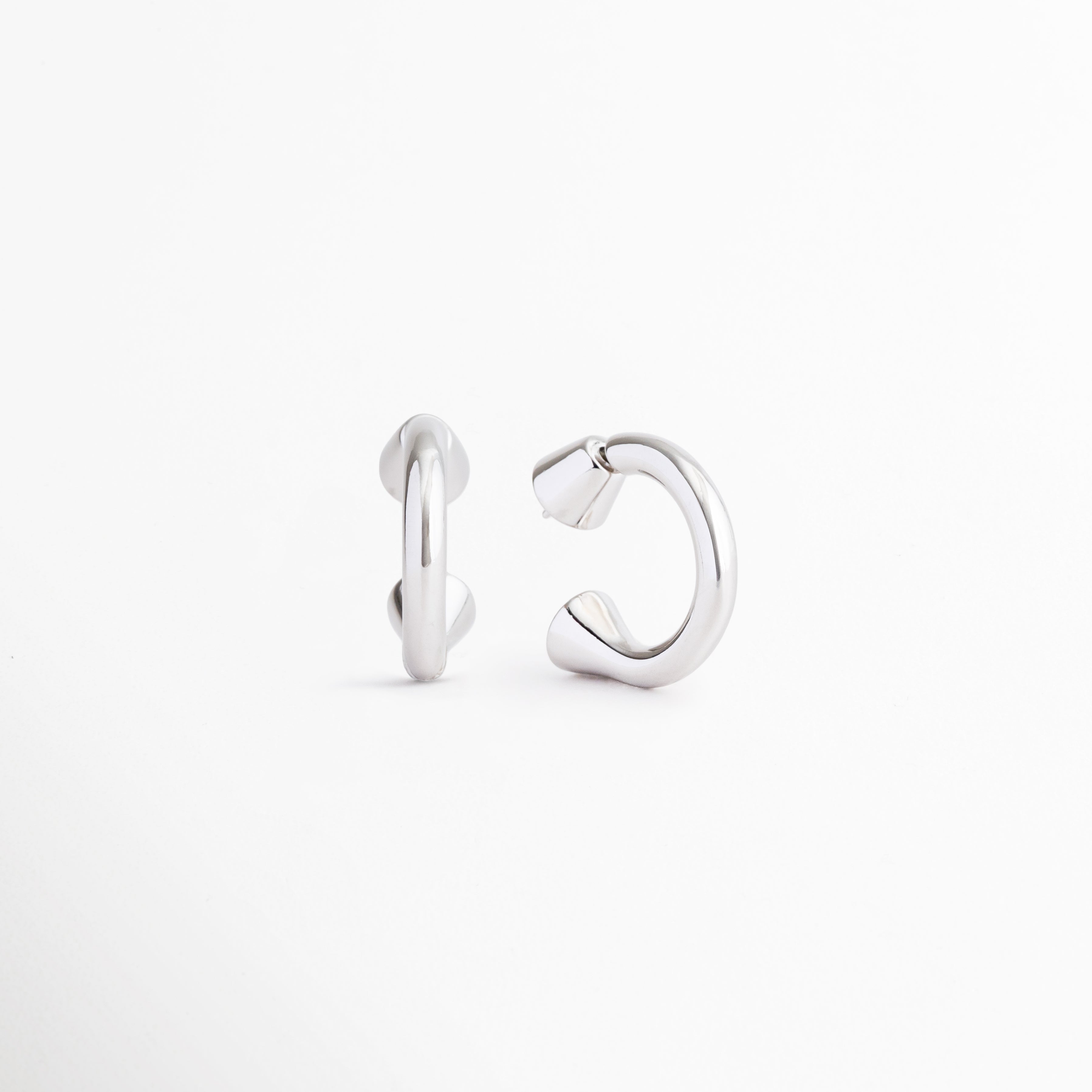 Perfil de los Aretes Virel con diseño geométrico y acabado en Plata 925, Vista lateral de aretes plateados modernos con estructura estilizada, Detalle del cierre y forma contemporánea de los Aretes Virel, Aretes plateados de diseño minimalista vistos de perfil, Vista lateral de aretes elegantes con acabado brillante y líneas limpias.
