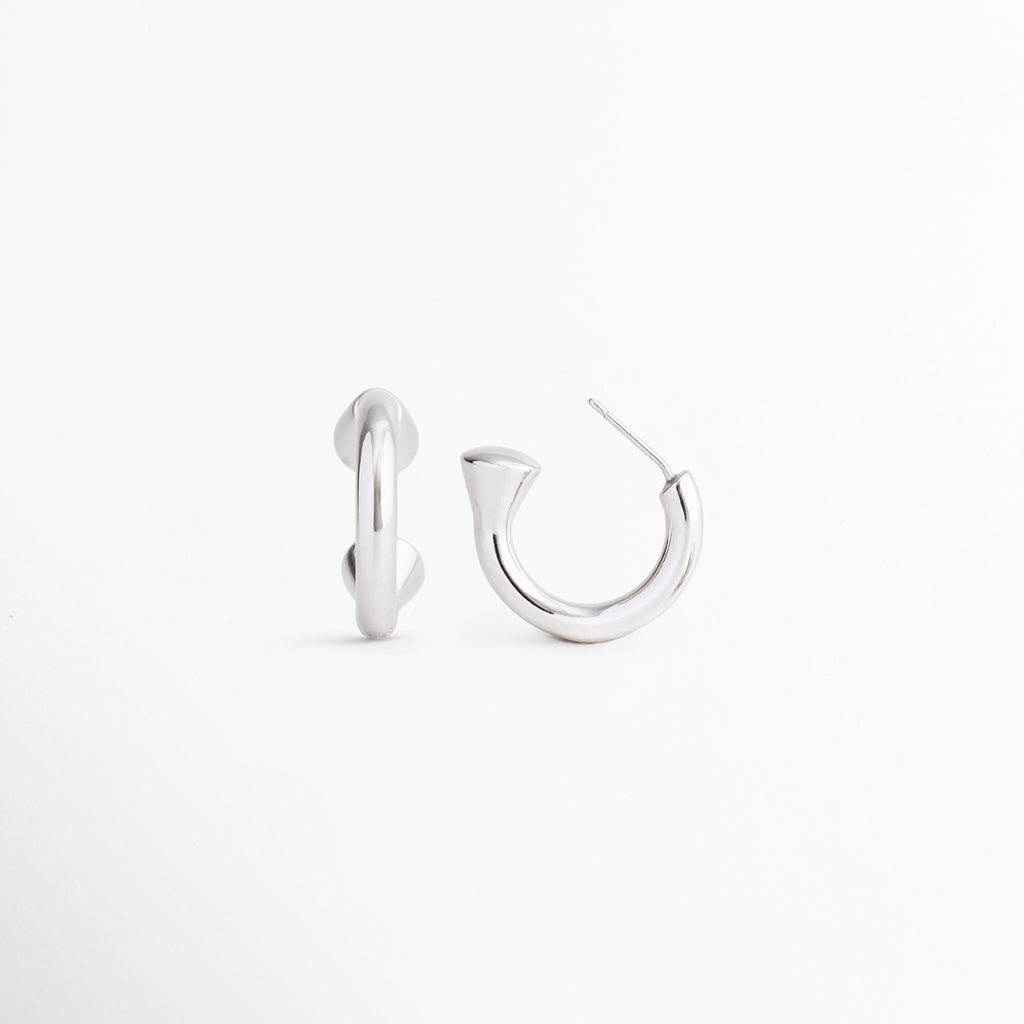 Aretes Virel plateados desde ángulo lateral mostrando su diseño geométrico, Detalle de aretes contemporáneos en Plata 925 con acabado pulido, Vista angular de aretes minimalistas y sofisticados para mujer, Aretes plateados de estilo moderno con silueta refinada, Detalle del diseño elegante y versátil de los Aretes Virel.