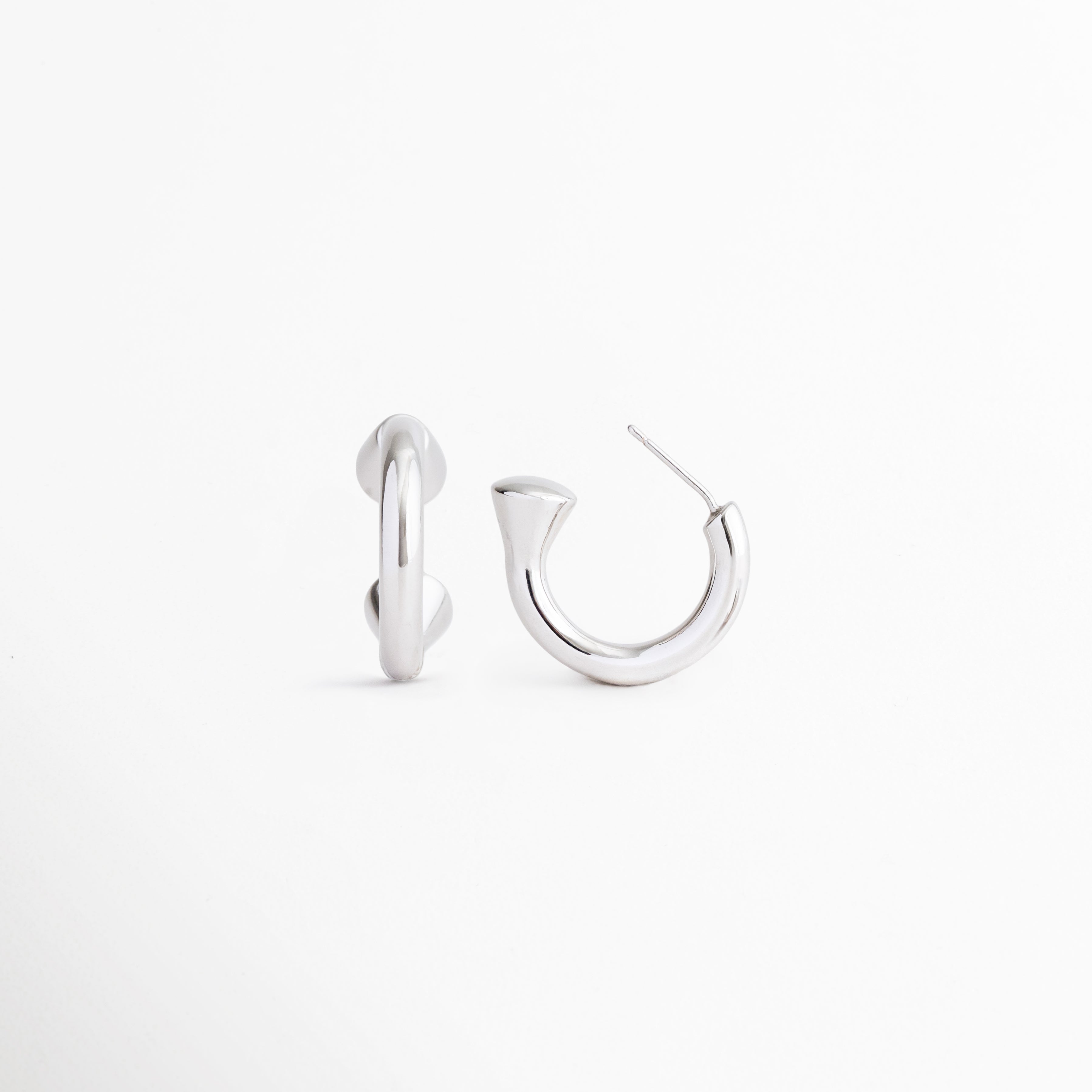 Aretes Virel plateados desde ángulo lateral mostrando su diseño geométrico, Detalle de aretes contemporáneos en Plata 925 con acabado pulido, Vista angular de aretes minimalistas y sofisticados para mujer, Aretes plateados de estilo moderno con silueta refinada, Detalle del diseño elegante y versátil de los Aretes Virel.